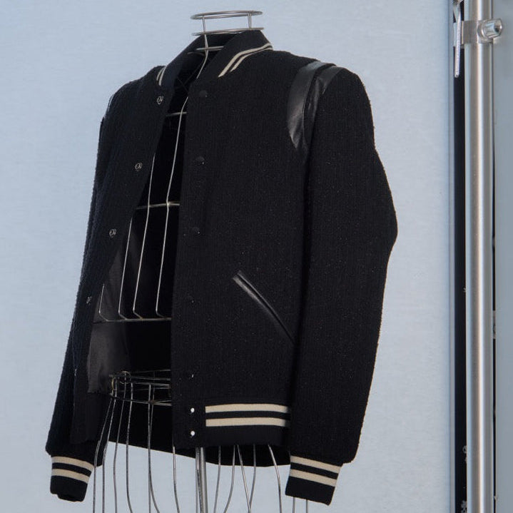 Black Saint Laurent varsity jacket with white accents on a mannequin against a light gray background