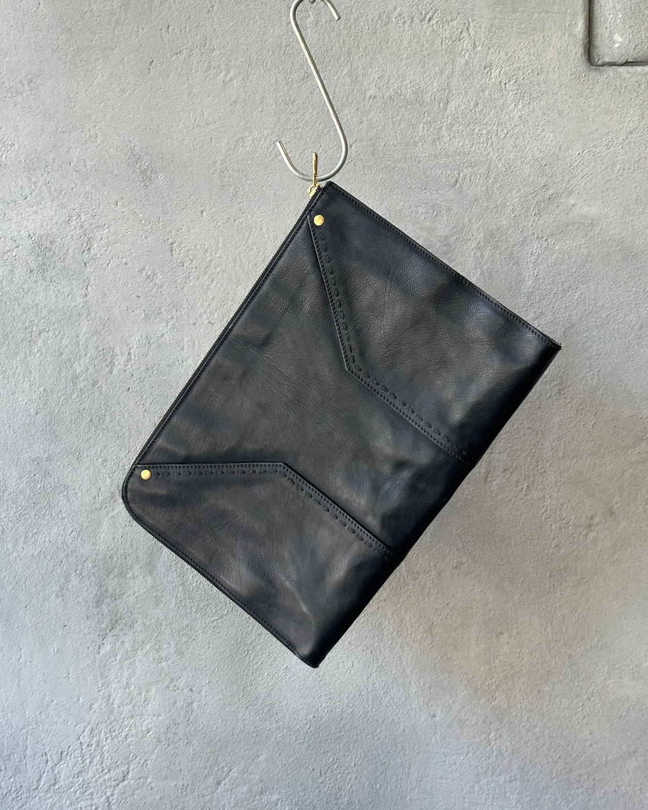 Black leather Saint Laurent clutch bag on a textured gray surface