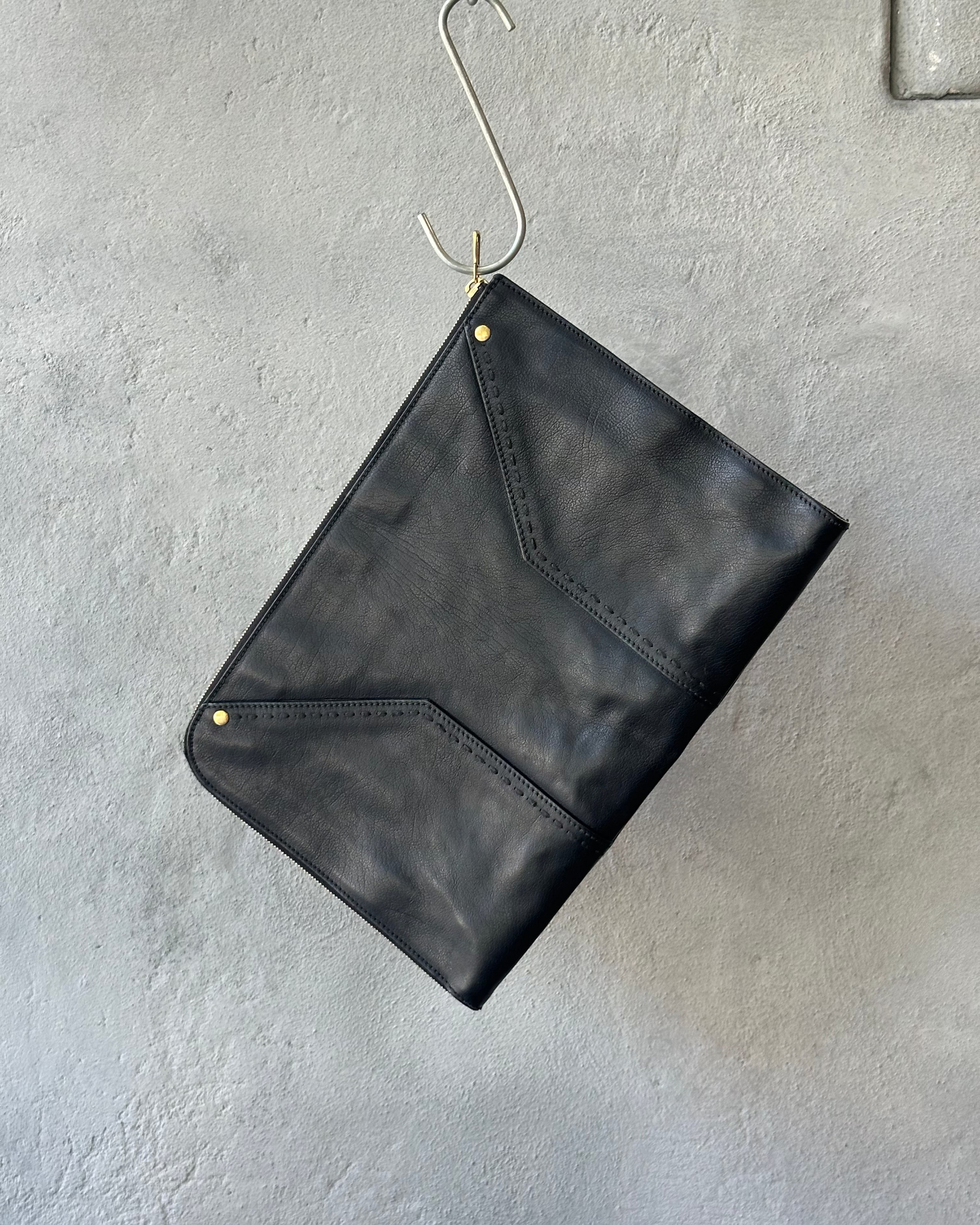Black leather Saint Laurent clutch bag on a textured gray surface