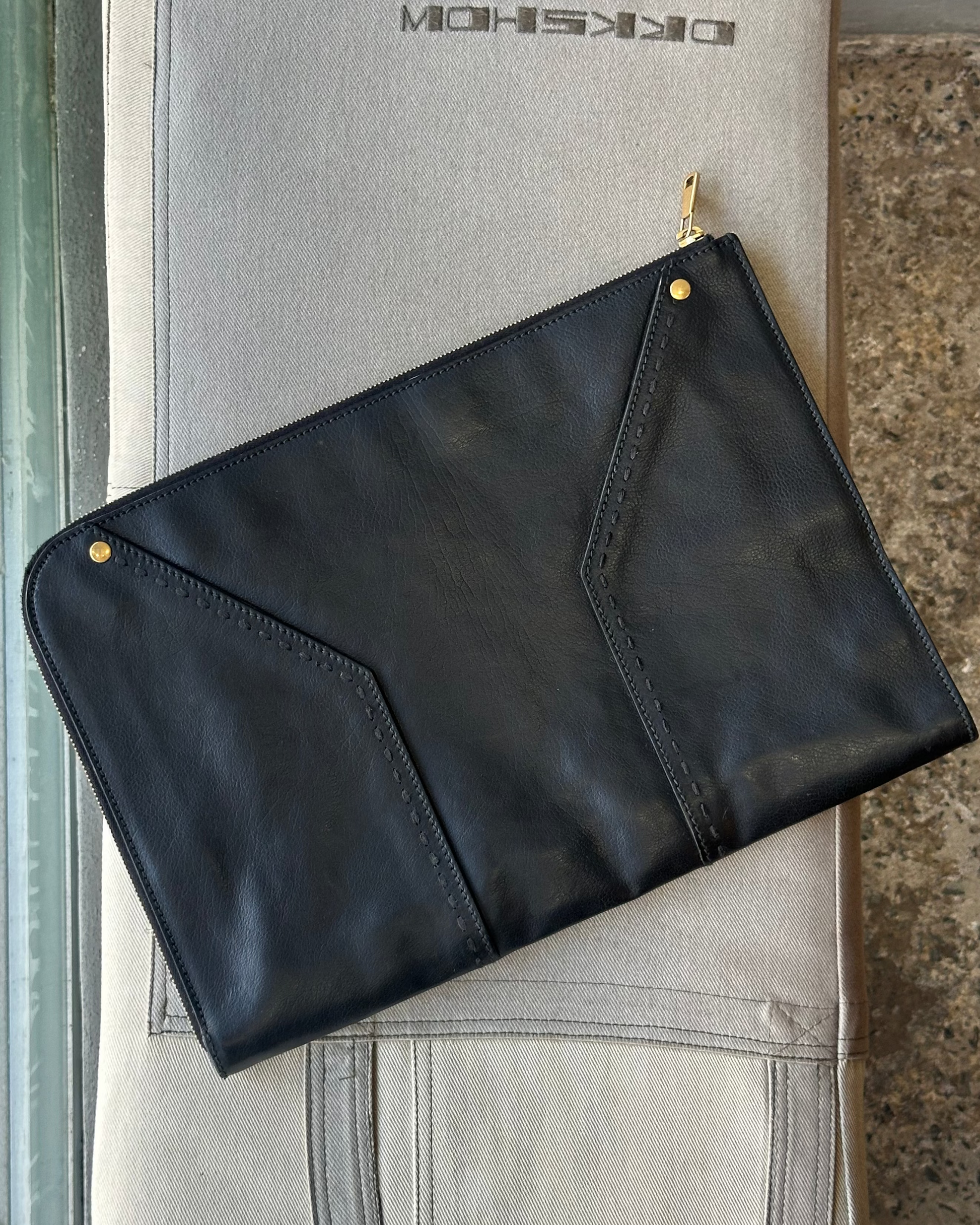 Black leather Saint Laurent portfolio wallet on a gray surface with branding.