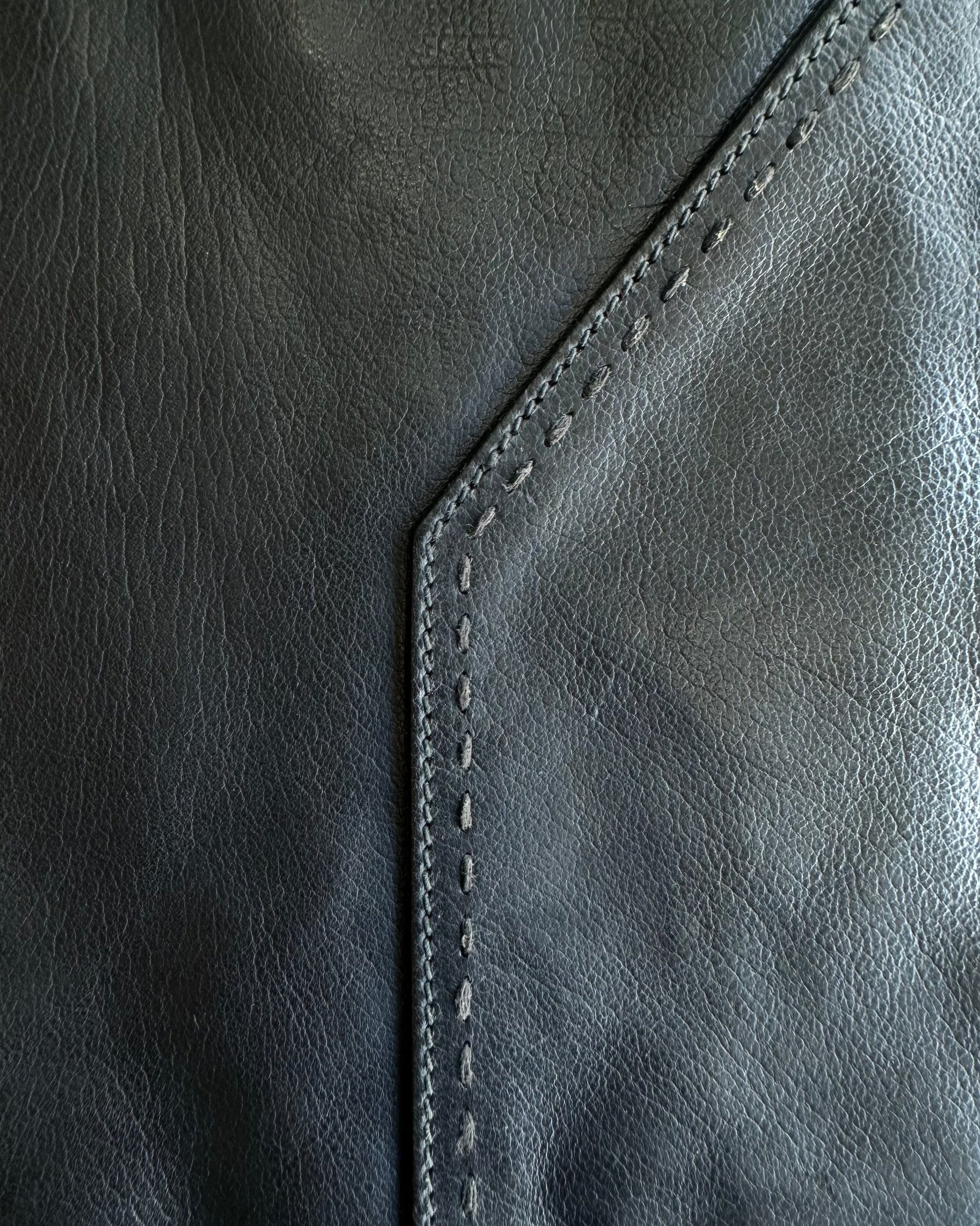 Close-up of a dark gray leather Saint Laurent portfolio surface with stitching detail