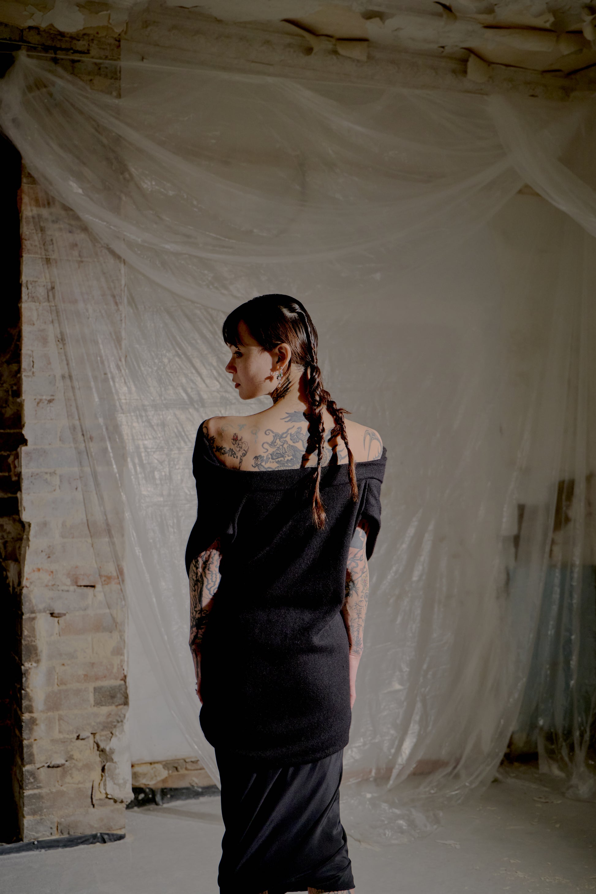 Woman in a black Saint Laurent dress standing in a room with white fabric draped around