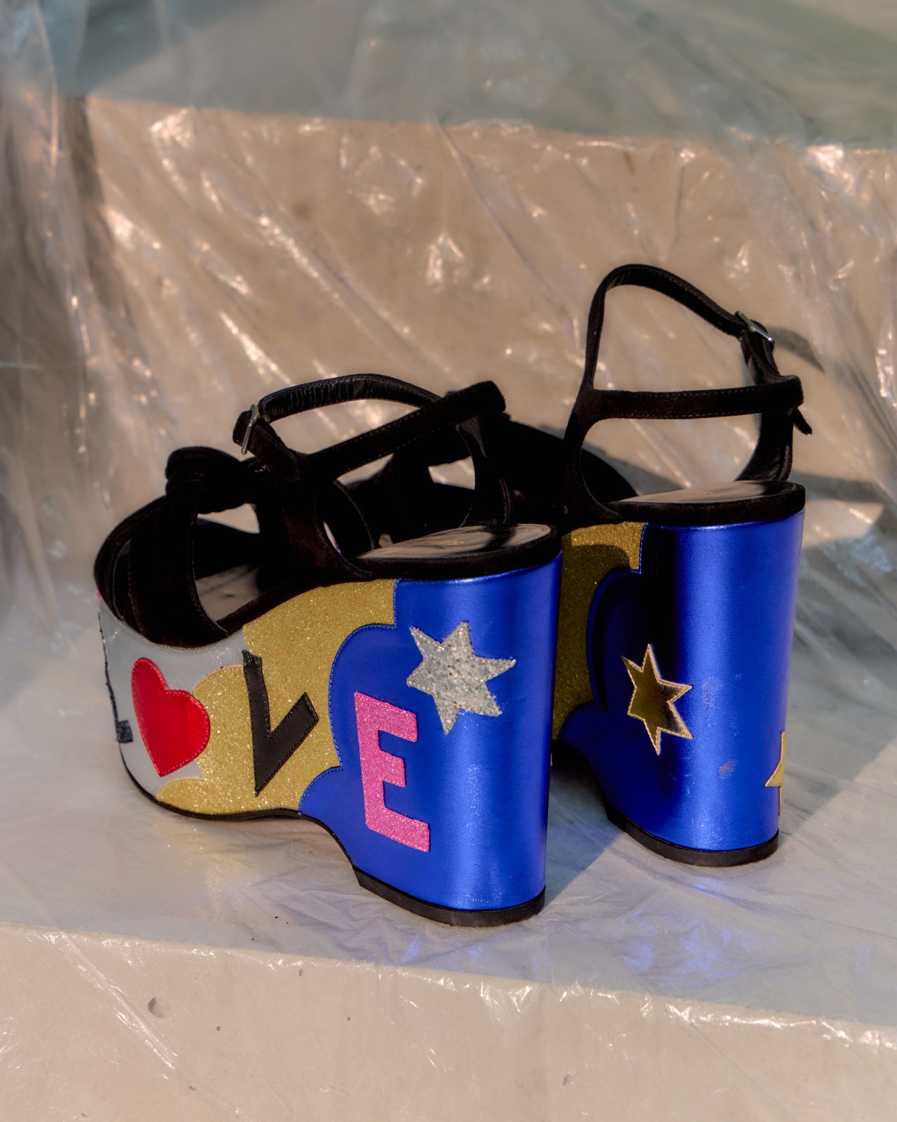 Black Saint Laurent platform sandals with colourful 'LOVE' design on a white surface