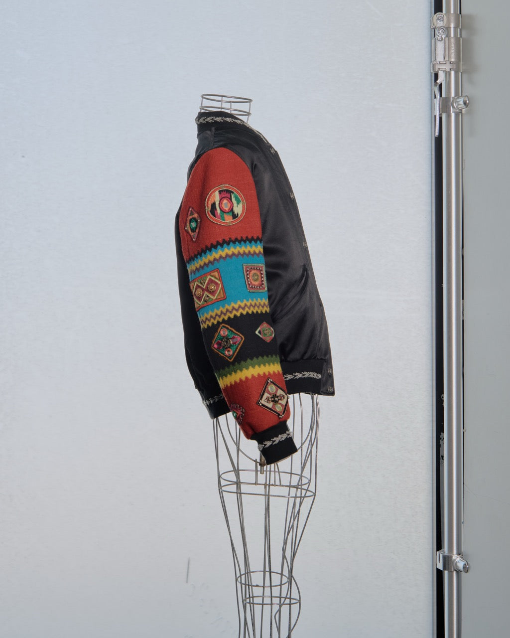 Colourful Saint Laurent jacket with geometric patterns on a mannequin against a plain background