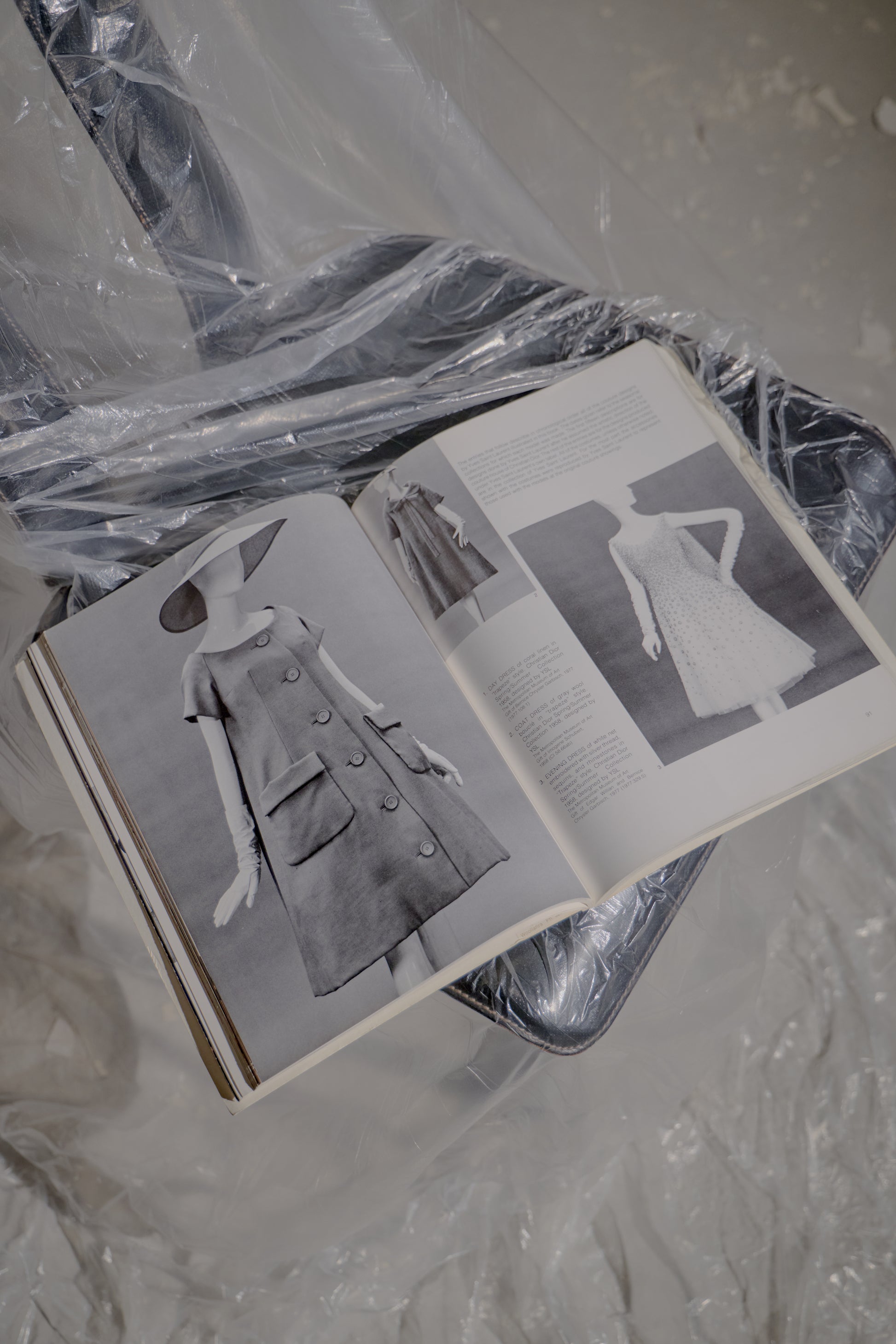 Open Saint Laurent book with fashion illustrations on a plastic-covered surface