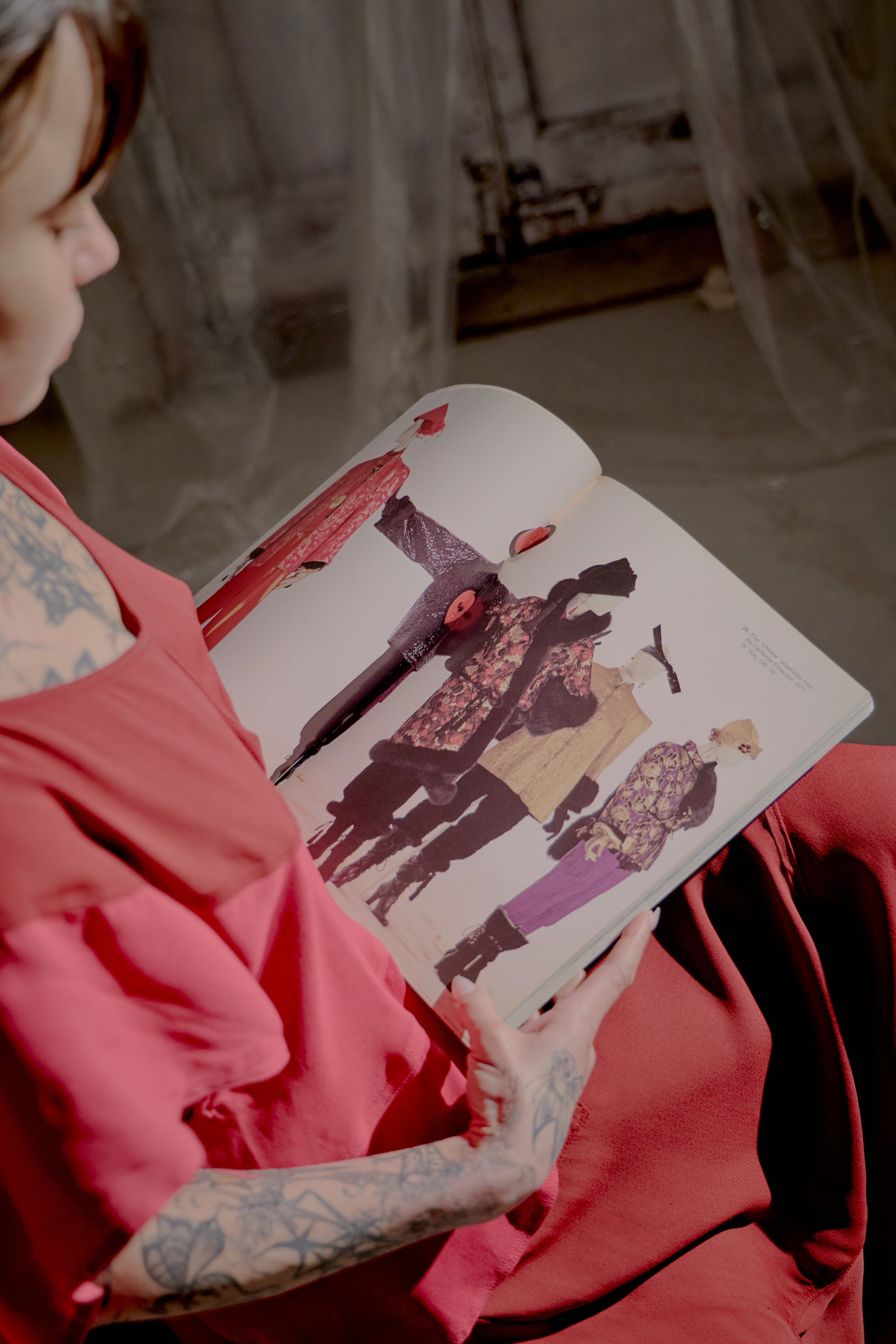 Person holding a Saint Laurent book with illustrations of people in various poses.