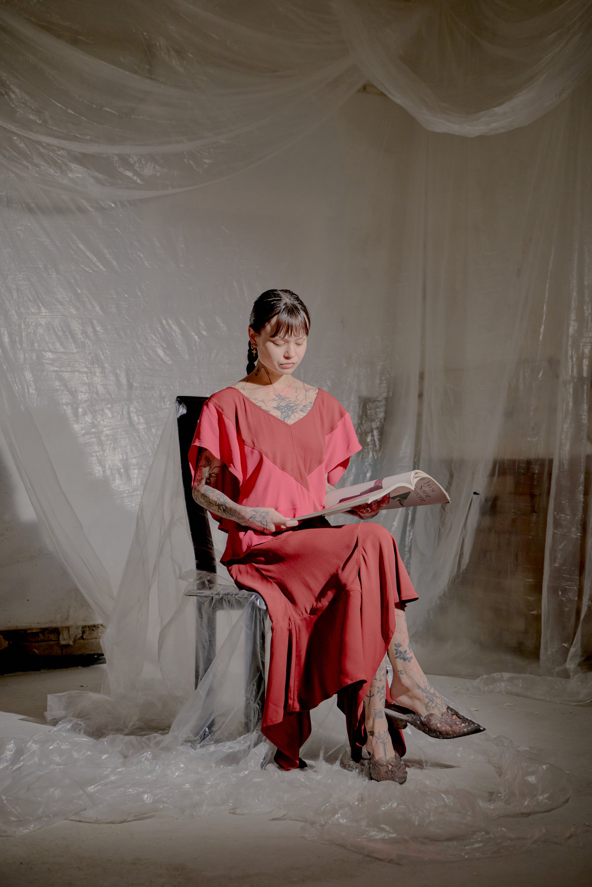 Woman in a red Saint Laurent dress sitting on a chair with white draped fabric in the background