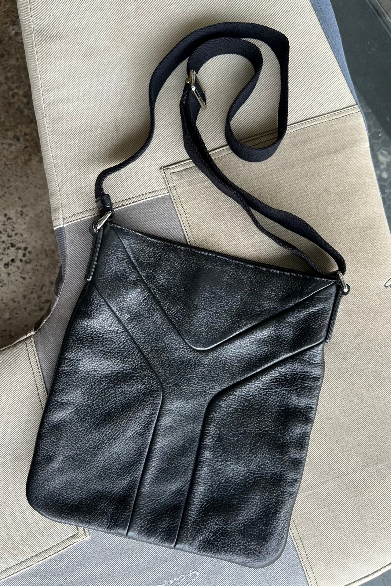 Black leather Saint Laurent messenger bag on a light gray surface