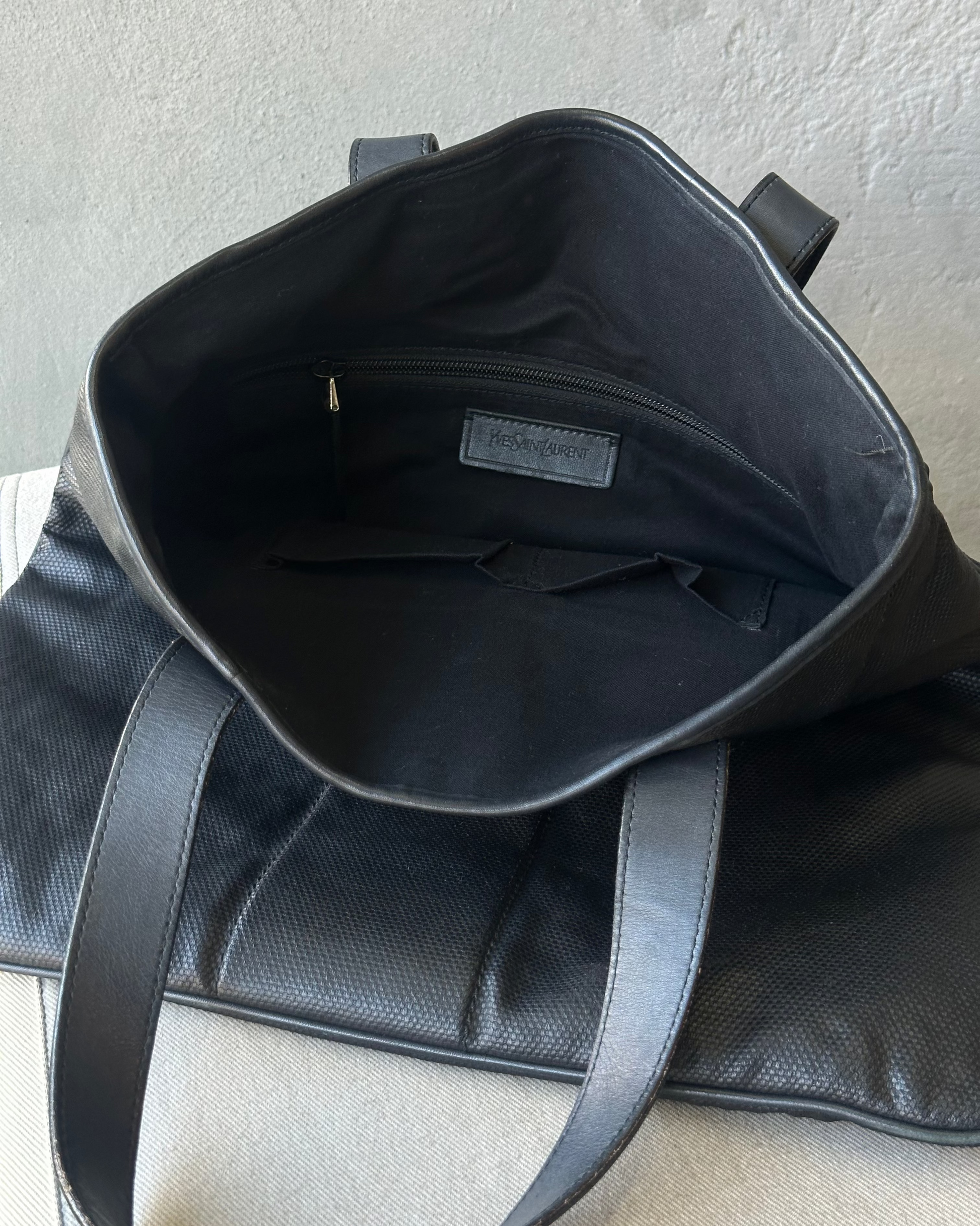 Black leather Saint Laurent bag with visible brand label on a neutral background