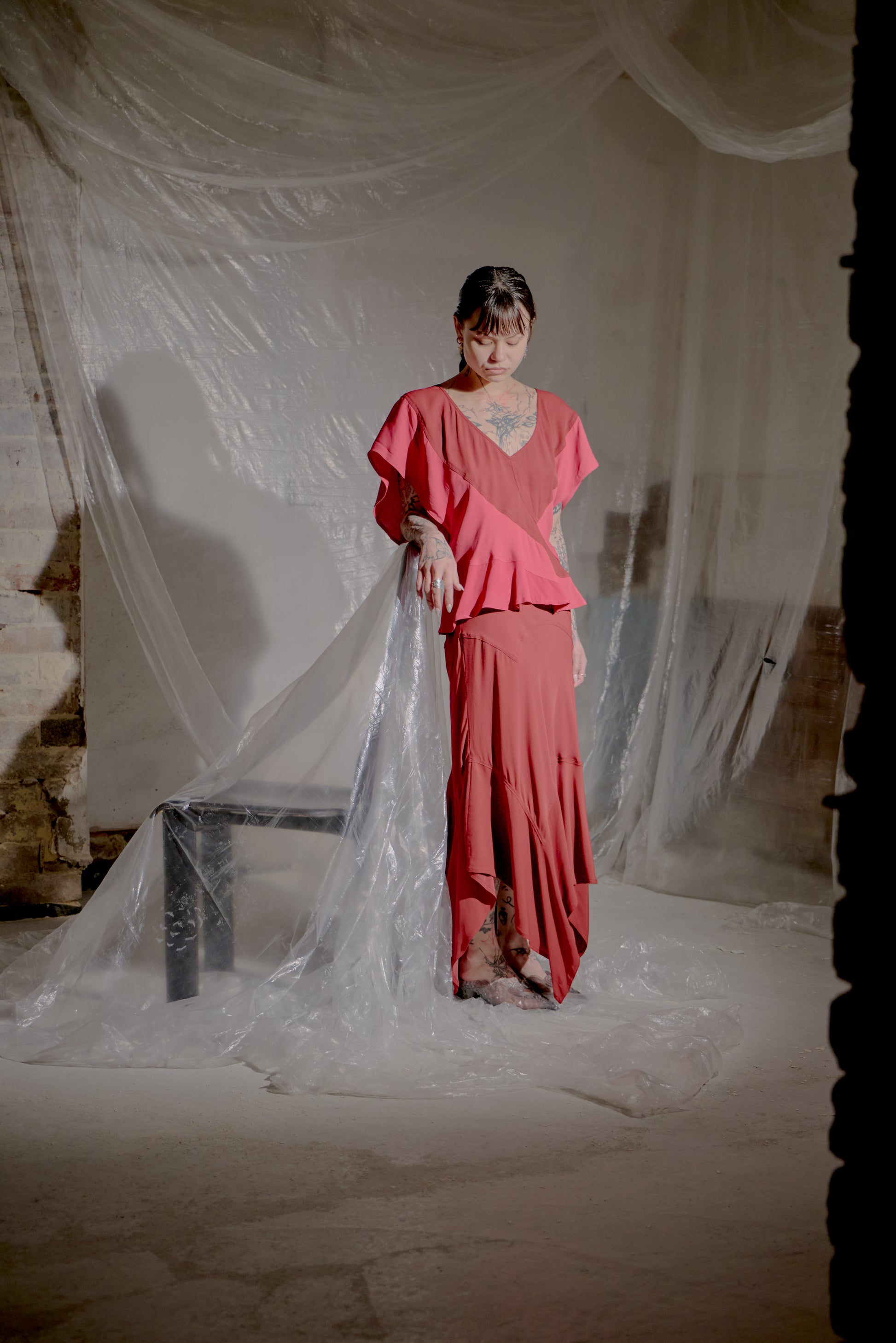 Woman in a pink Saint Laurent outfit standing in front of draped fabric