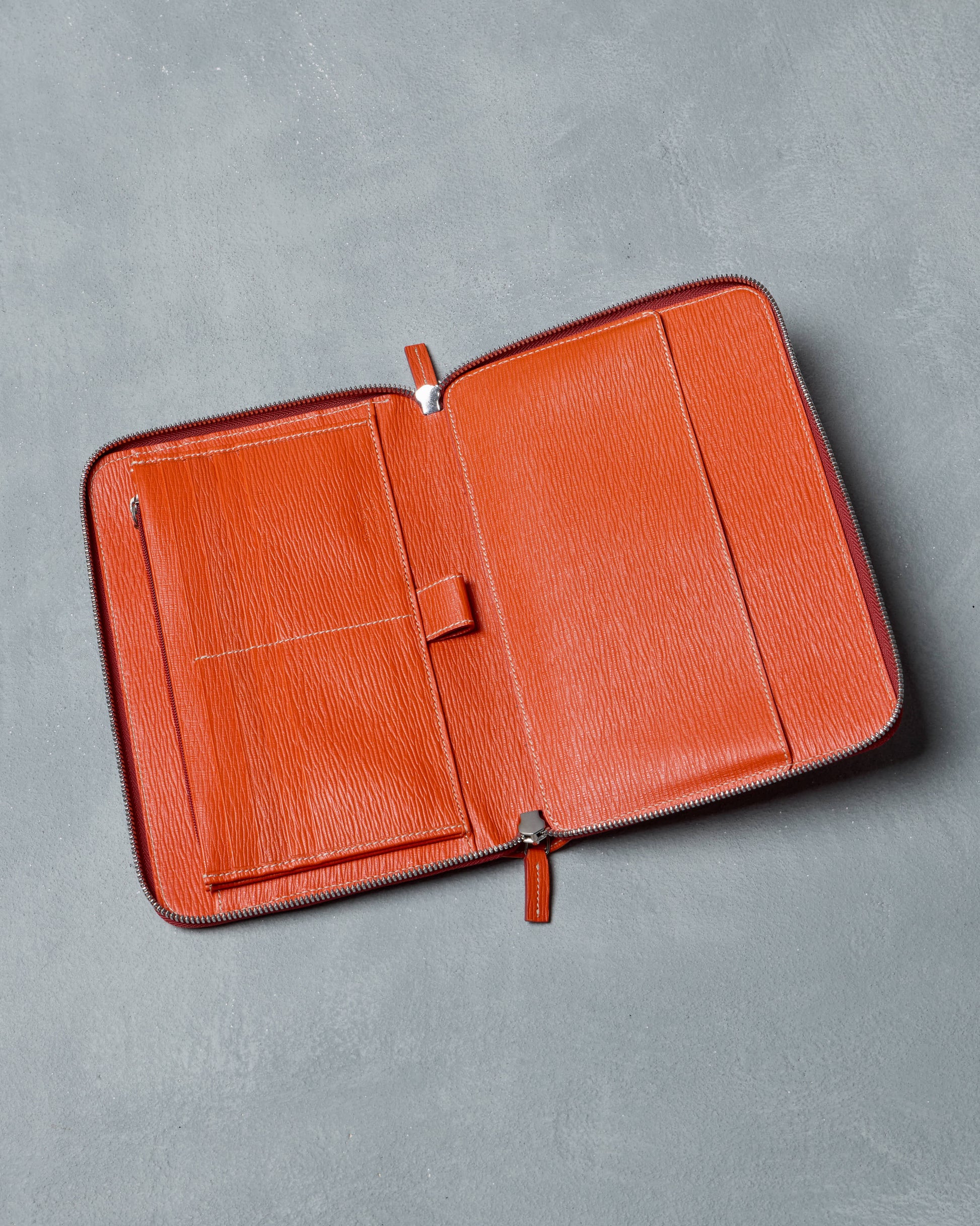 Orange leather Salvatore Ferragamo wallet on a gray background