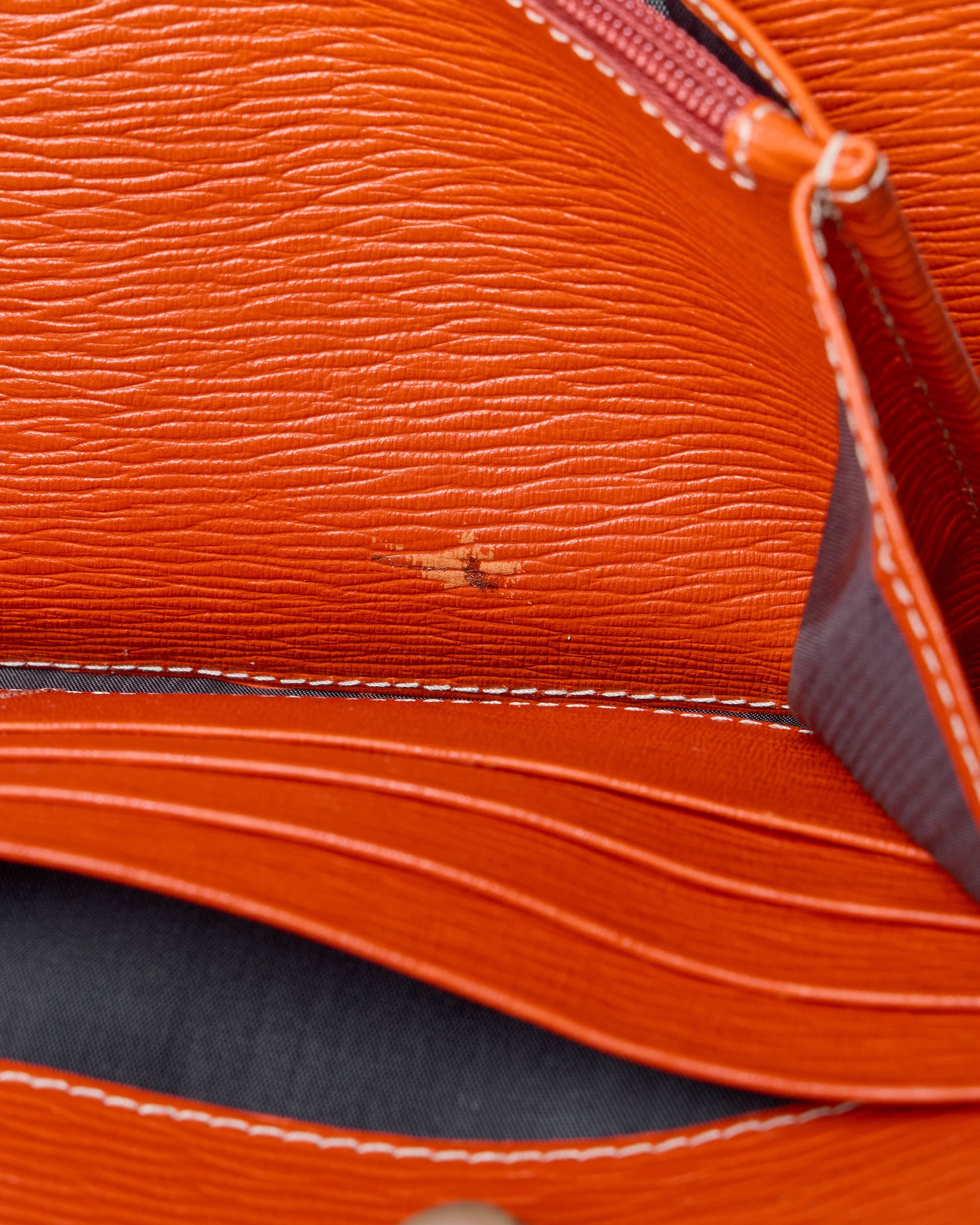 Close-up of an orange leather Salvatore Ferragamo bag with visible stitching
