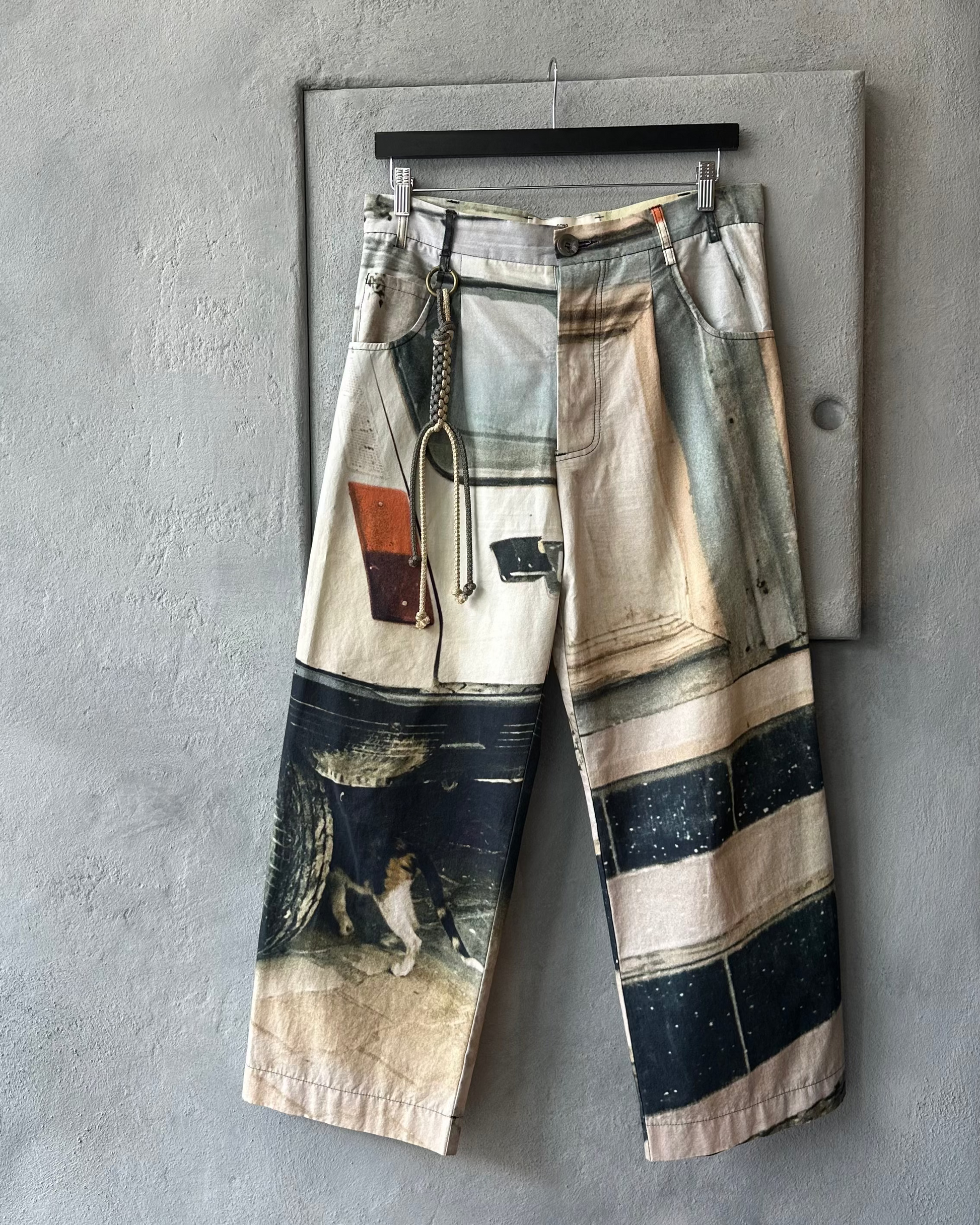 Song For The Mute Pants with abstract design hanging on a gray wall