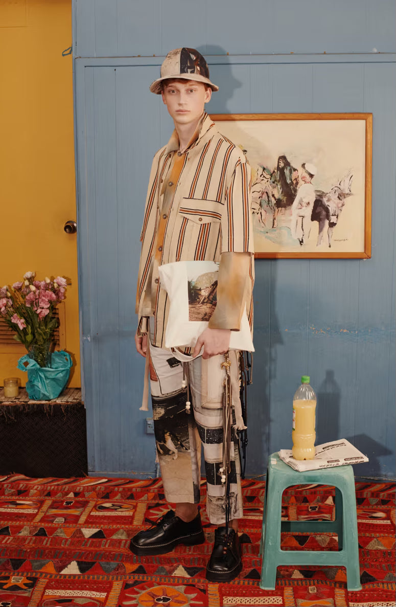 Person wearing a patterned Song For The Mute outfit in a room with a blue wall, yellow door, and colourful rug.