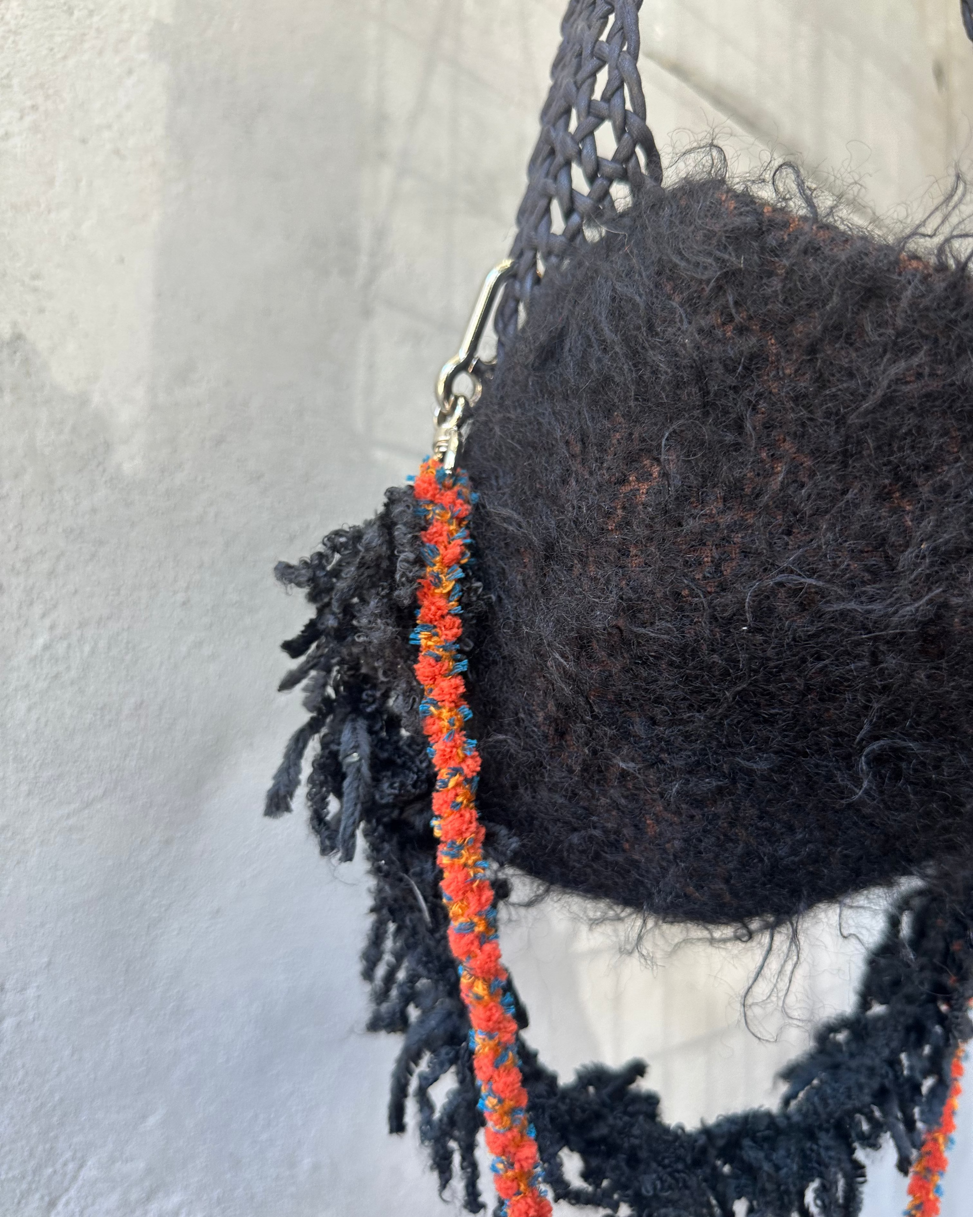 Black knitted Song For The Mute bag with orange beads on a white background