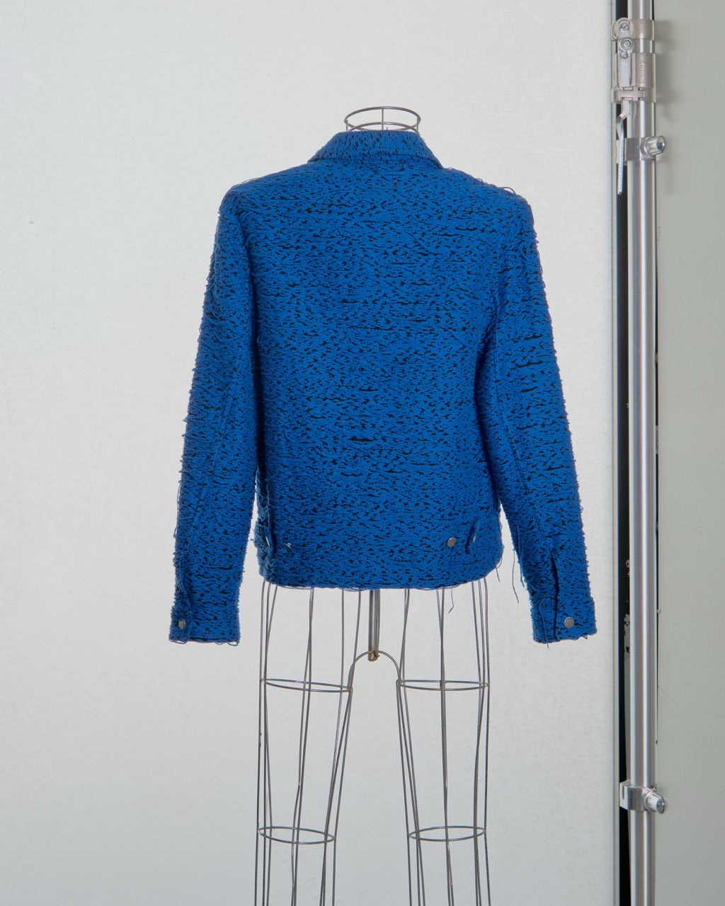 Blue textured Song For The Mute jacket on a mannequin against a white background