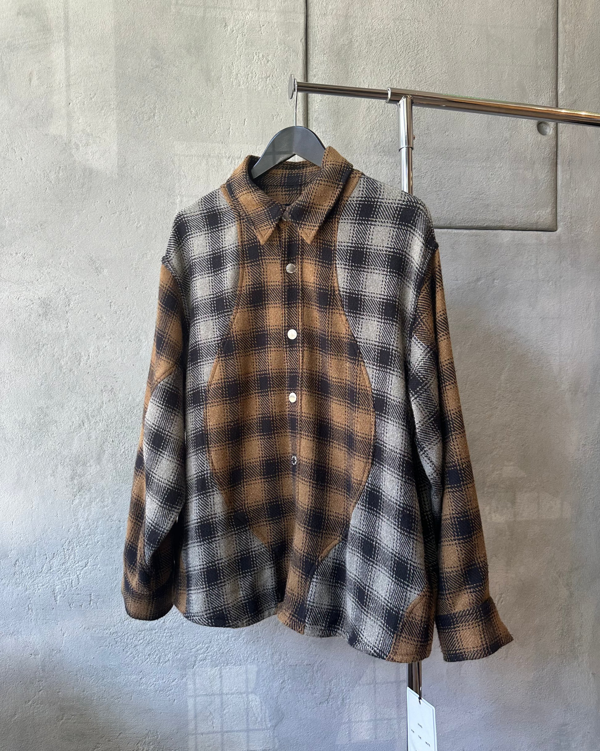 Plaid Song For The Mute shirt hanging on a rack against a gray wallng