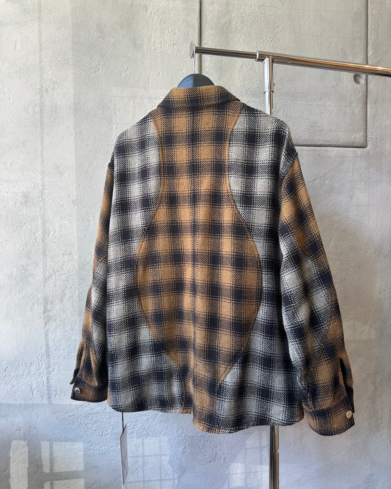 Plaid Song For The Mute shirt hanging on a rack against a gray wallng