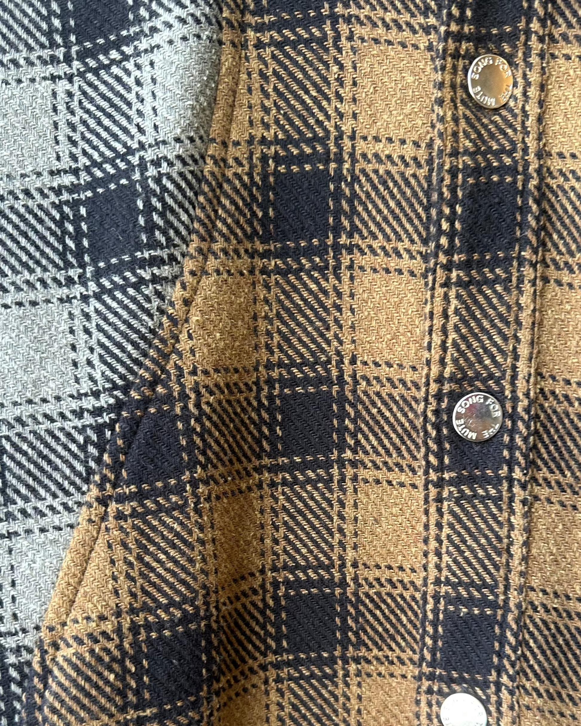 Close-up of a plaid Song For The Mute shirt with a focus on the fabric pattern and buttons.