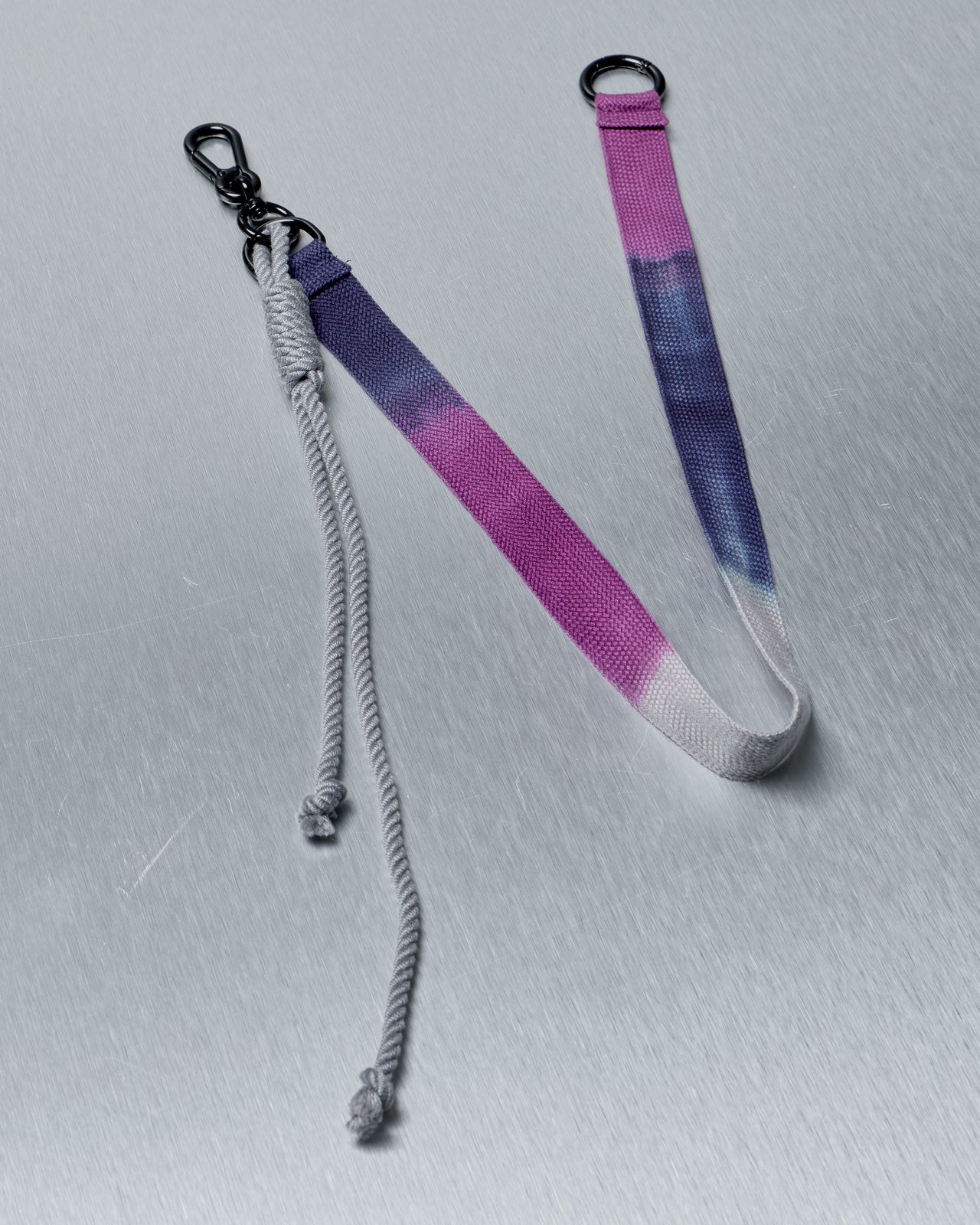 Gradient purple to gray Song For The Mute lanyard with metal clip on a light gray background