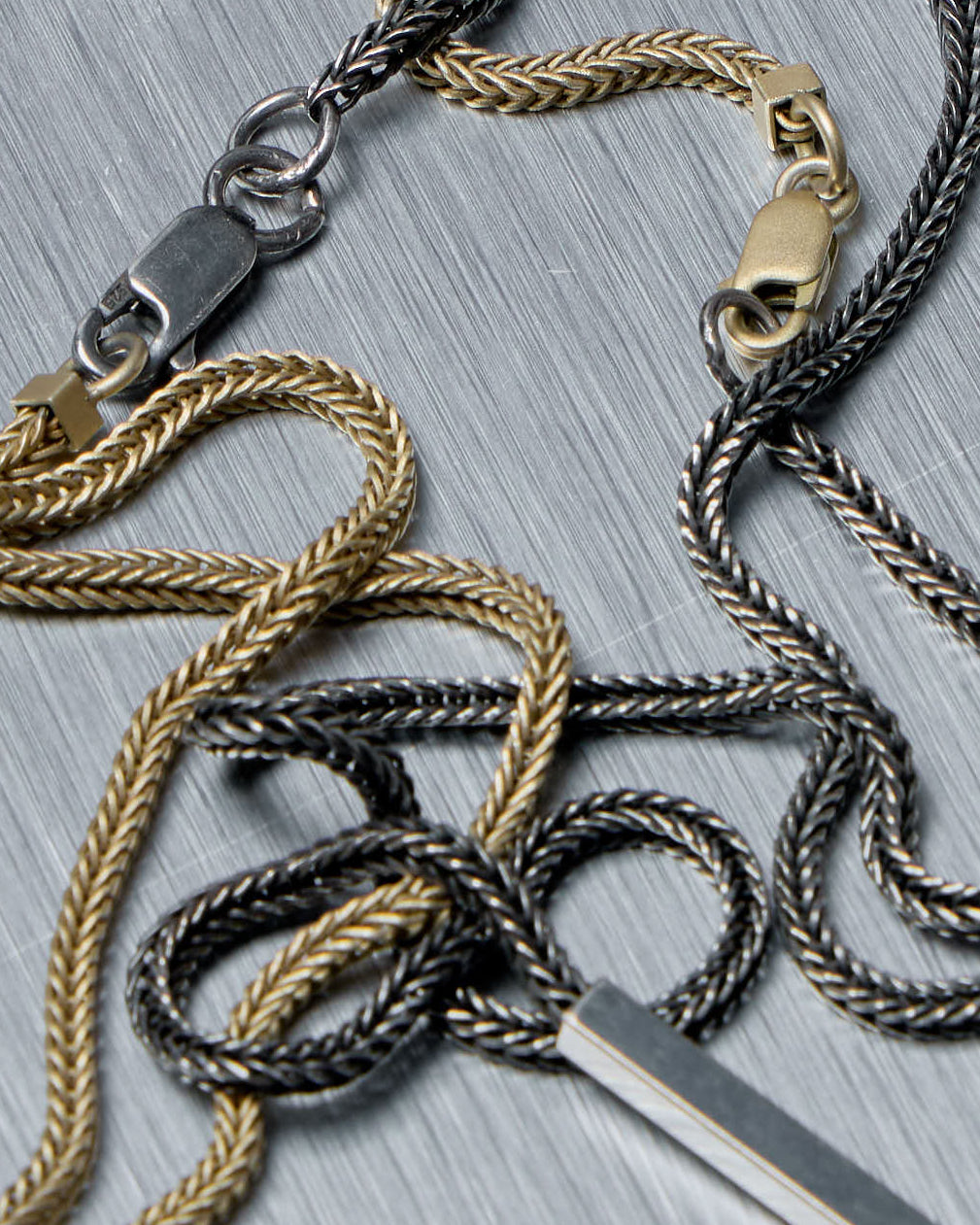 Long thin metal Stephanie Said necklace on a gray background