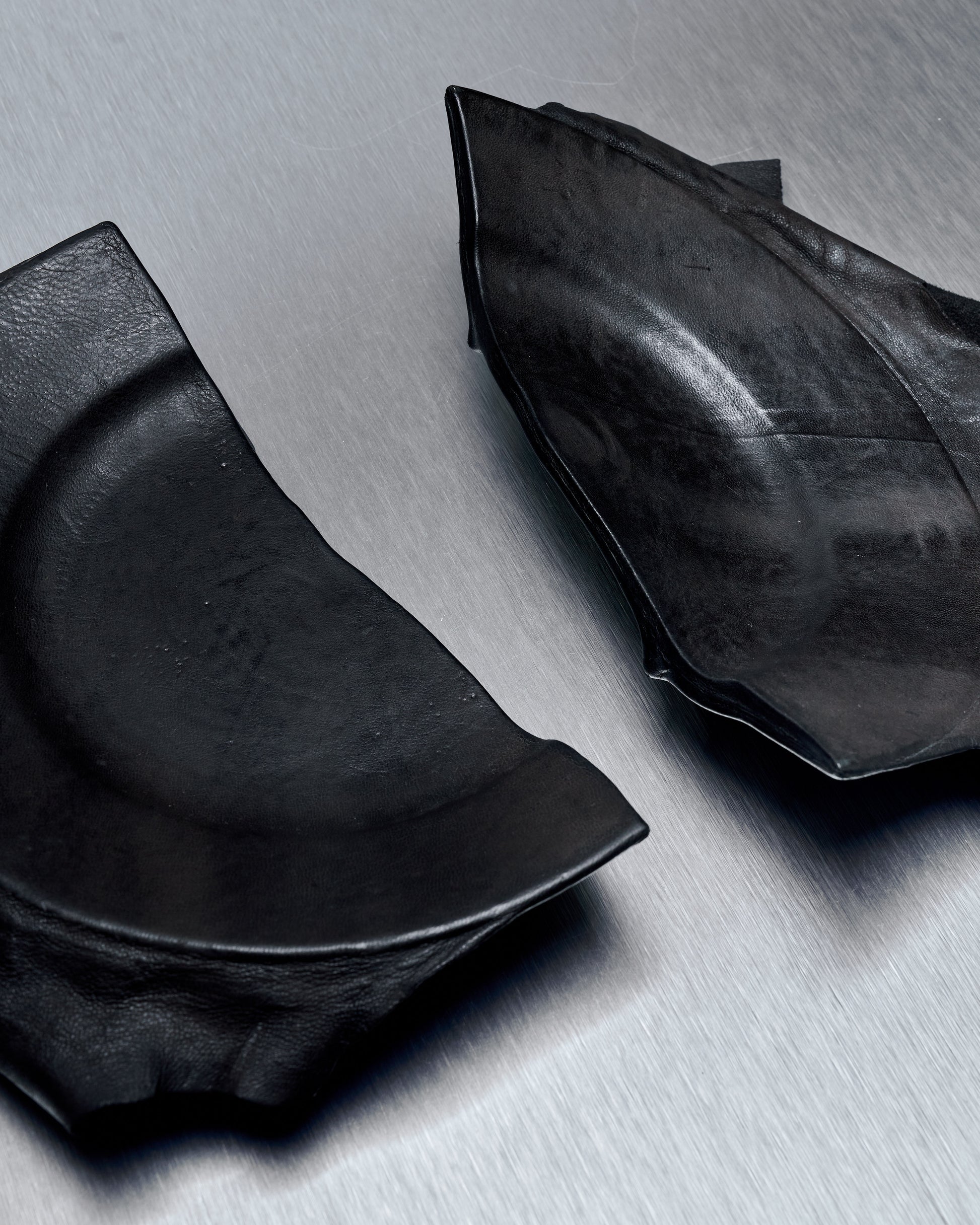 A photo of a ceramic plate from T.A.S Japan with a black lamb leather cover, showcasing the broken and repaired portions of the plate.