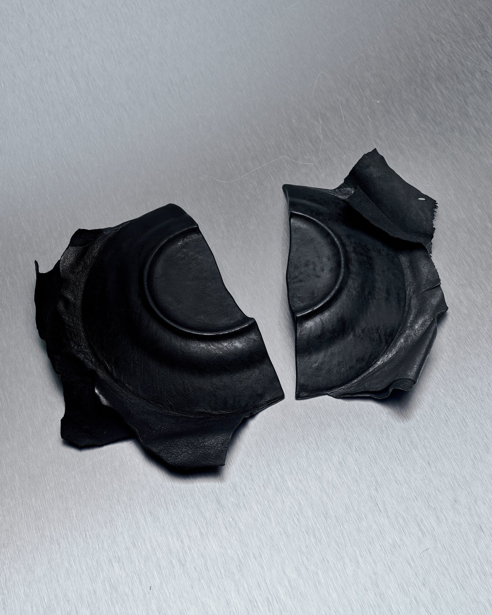 A photo of a the reverse of a ceramic plate from T.A.S Japan with a black lamb leather cover, showcasing the broken and repaired portions of the plate.