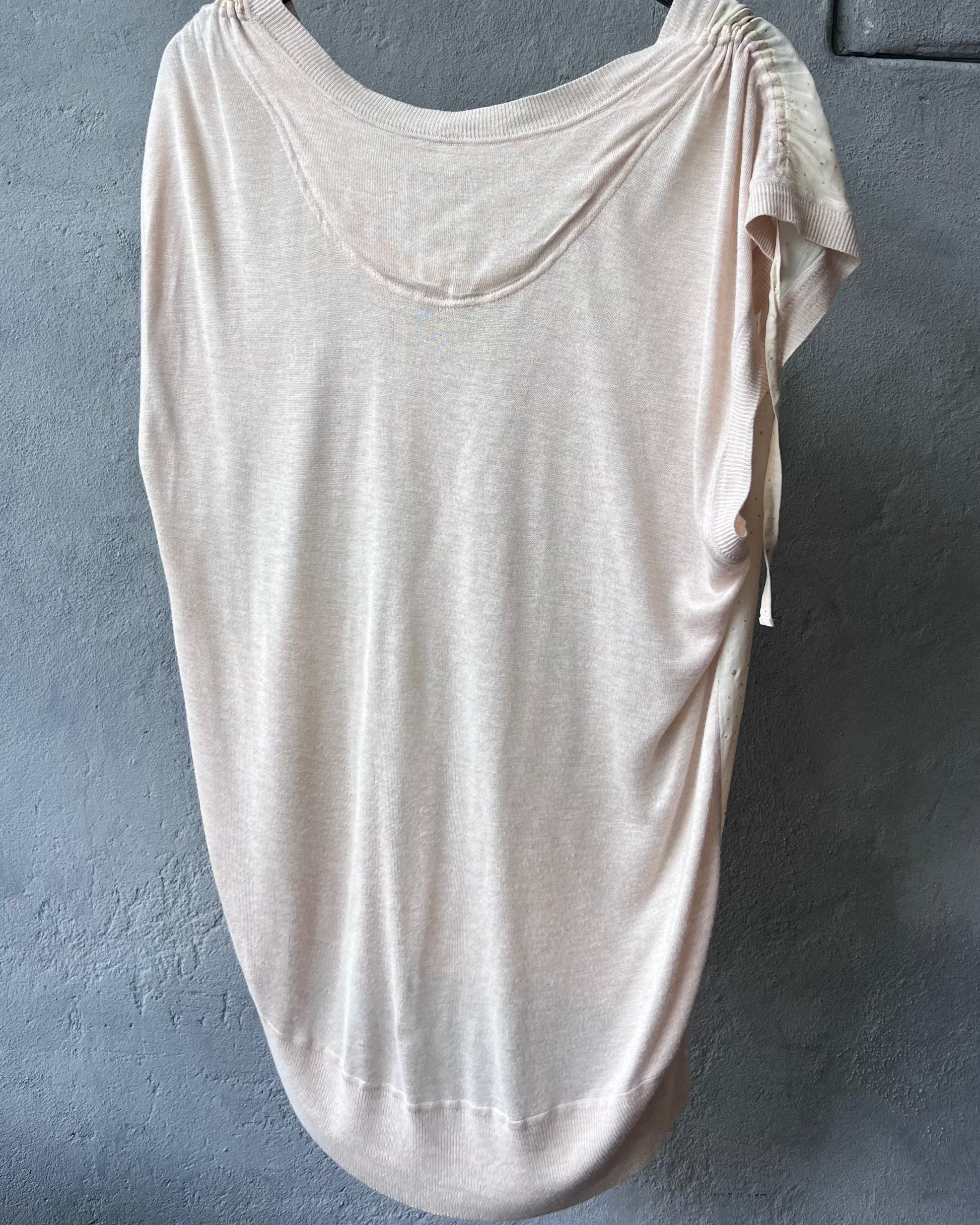 Beige Tsumori Chisato top on a hanger against a gray wall