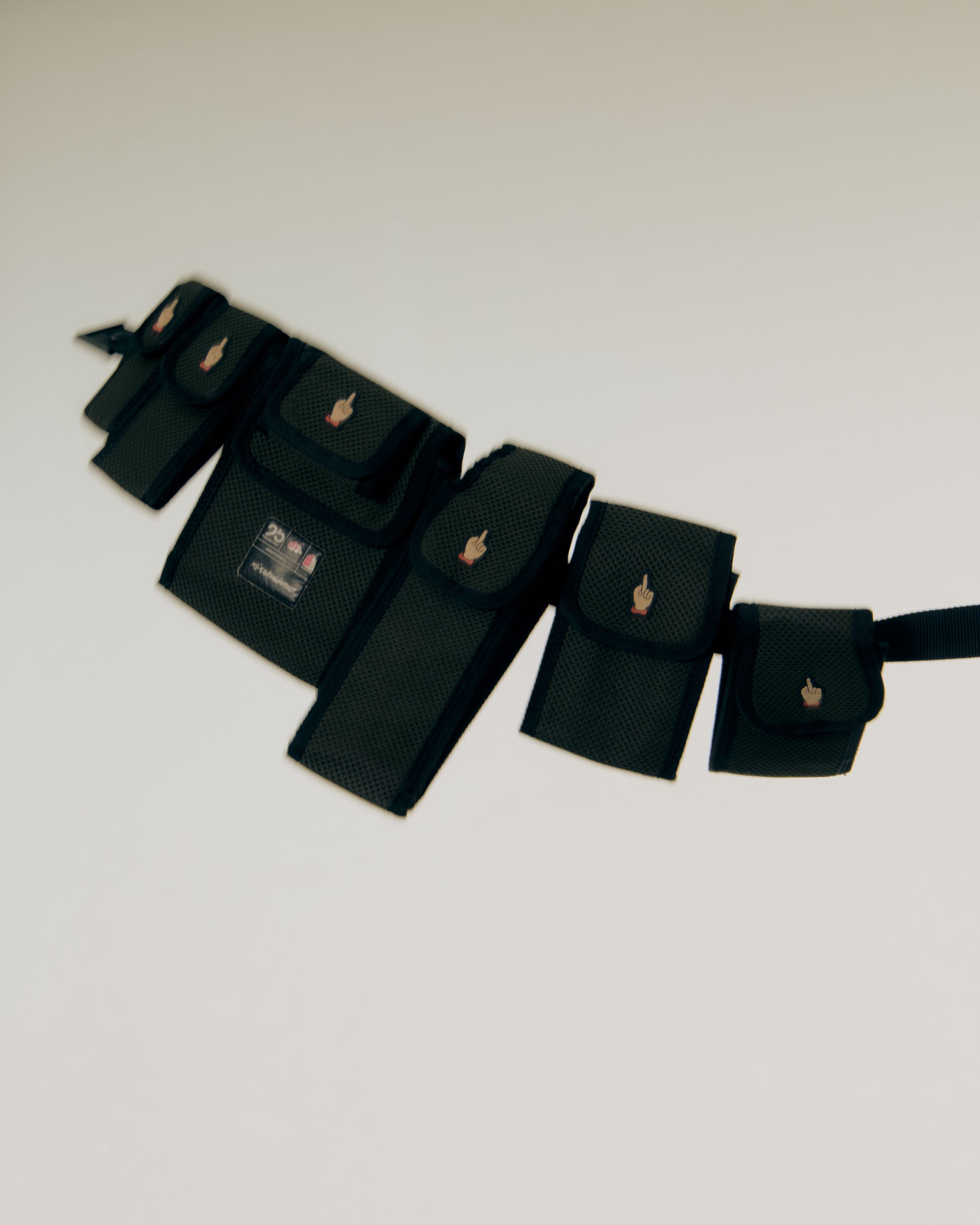 Set of black Undercover pouches with gold buckles on a light gray background