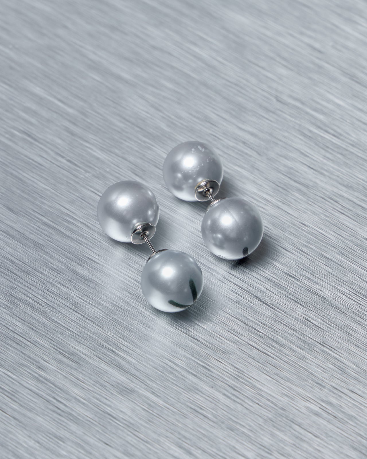 Set of baby blue Vetements earrings on a textured gray surface