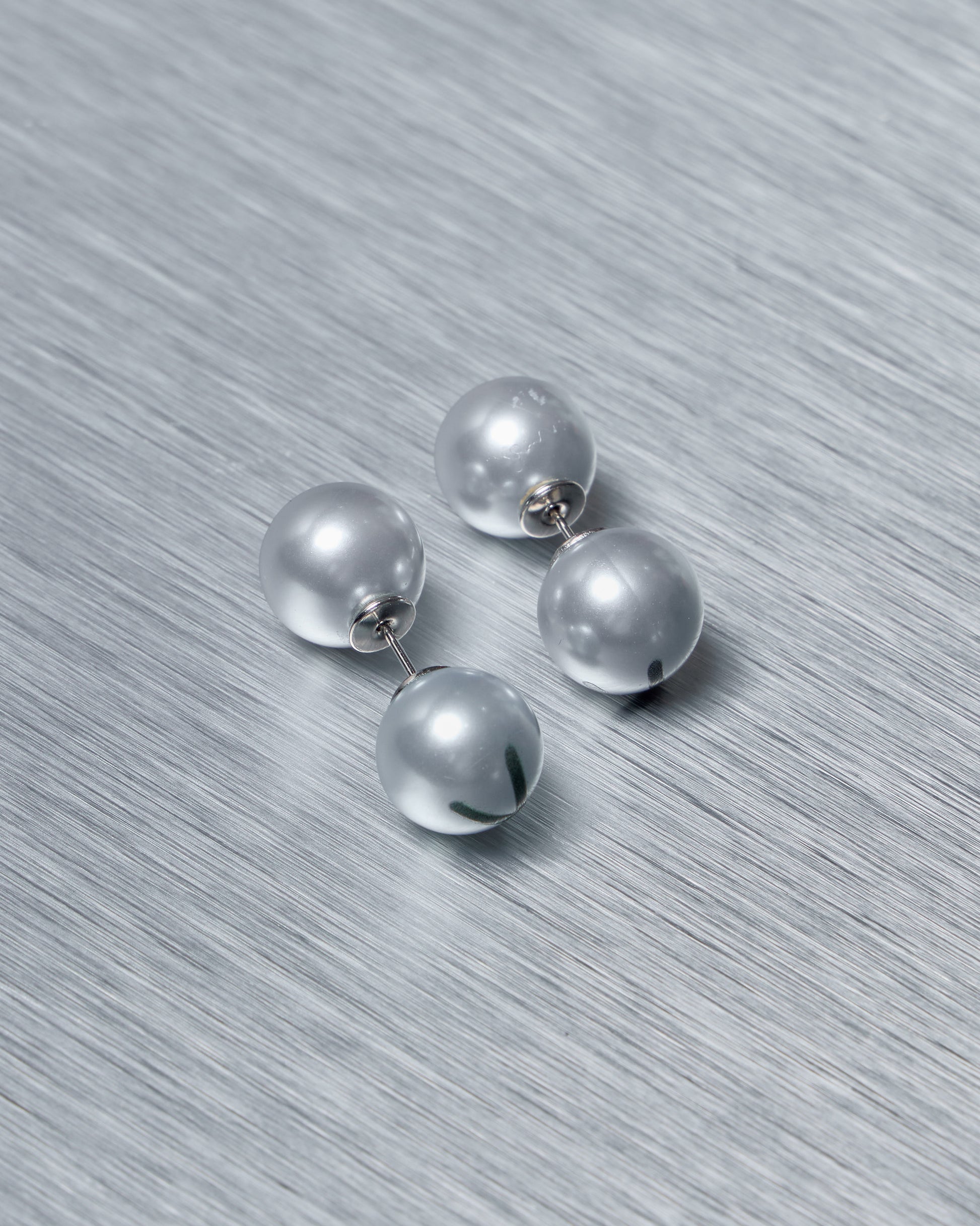 Set of baby blue Vetements earrings on a textured gray surface