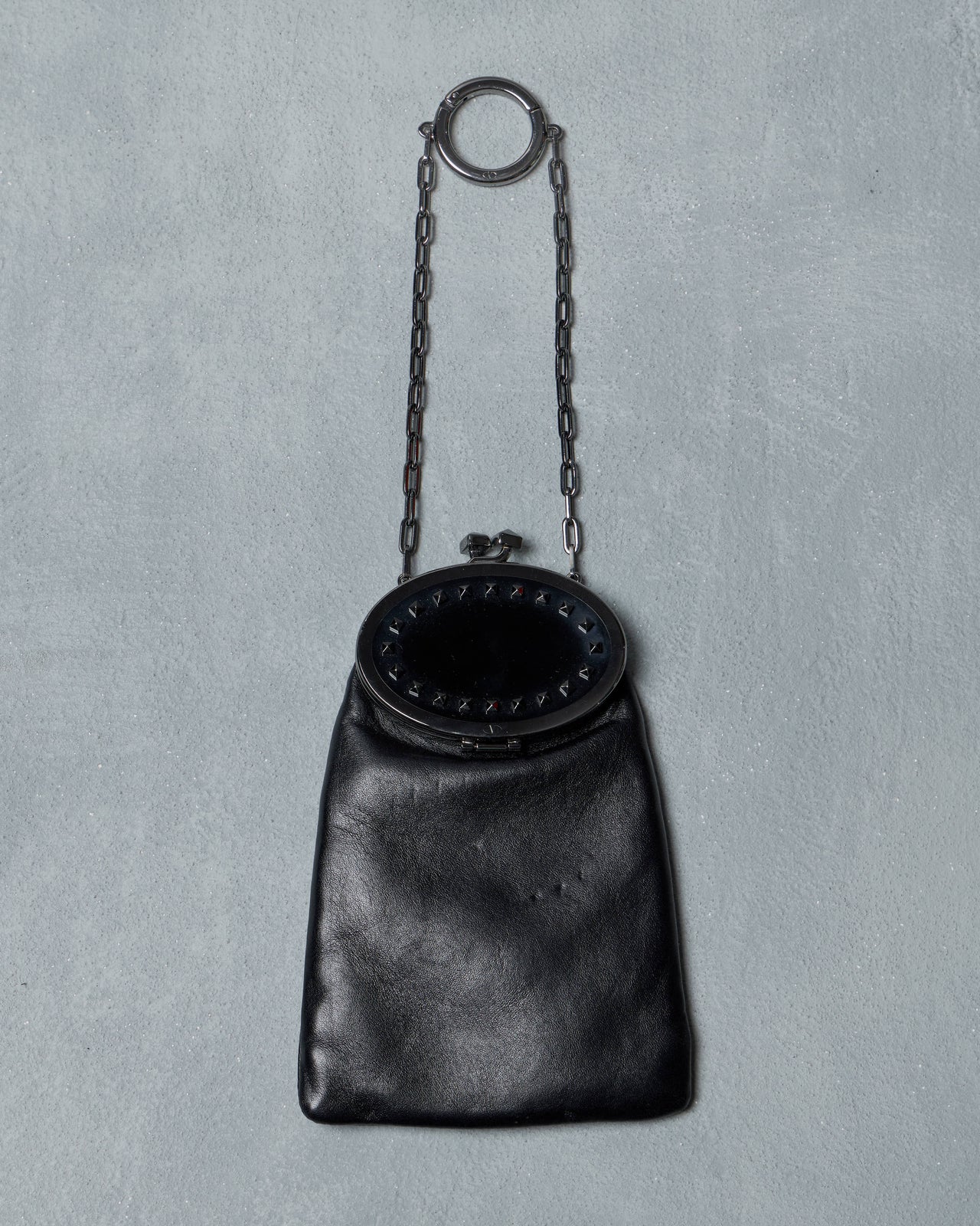 Black leather Valentino handbag with chain handle on a gray background