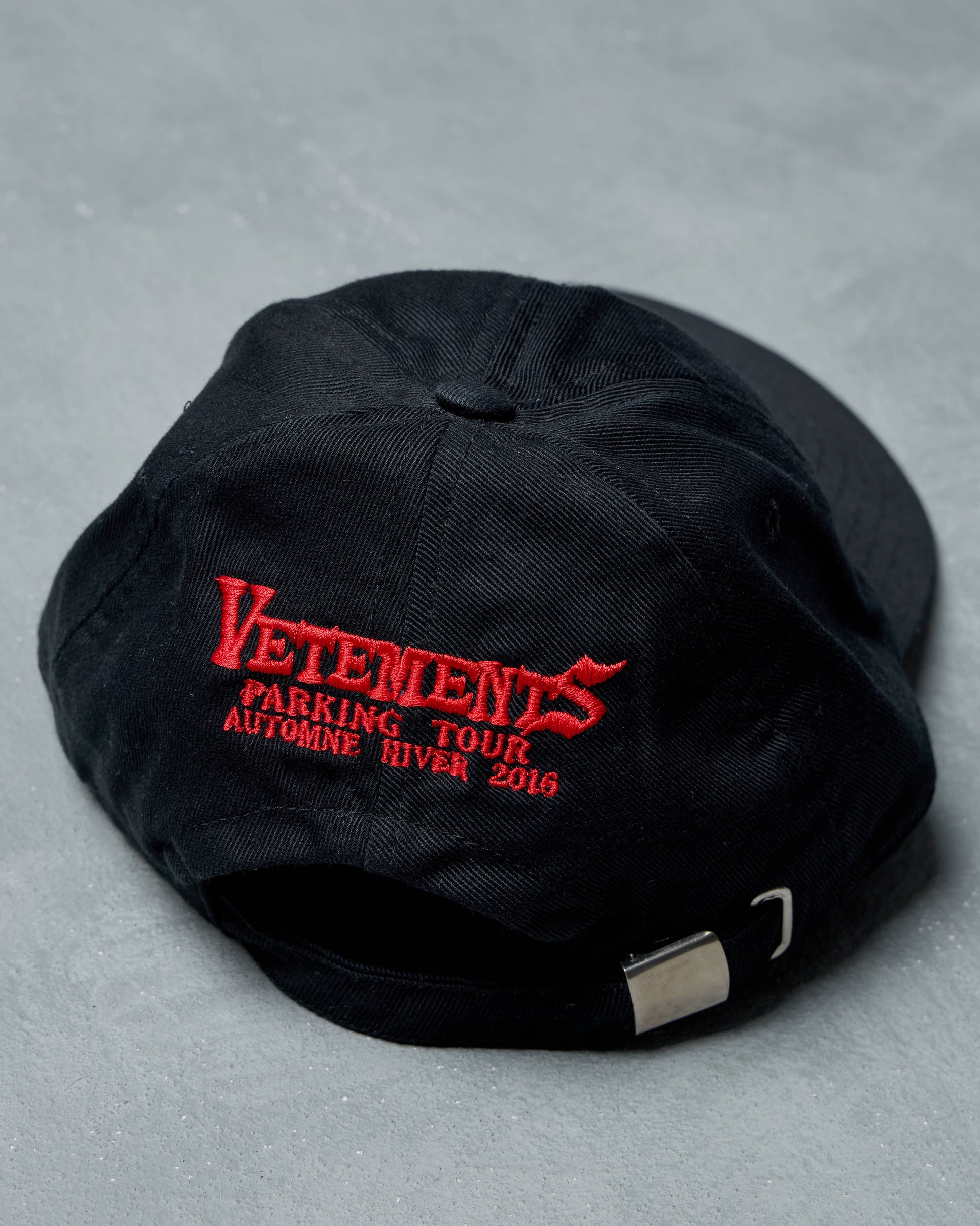 Black cap with red 'Vetements' logo on a gray background