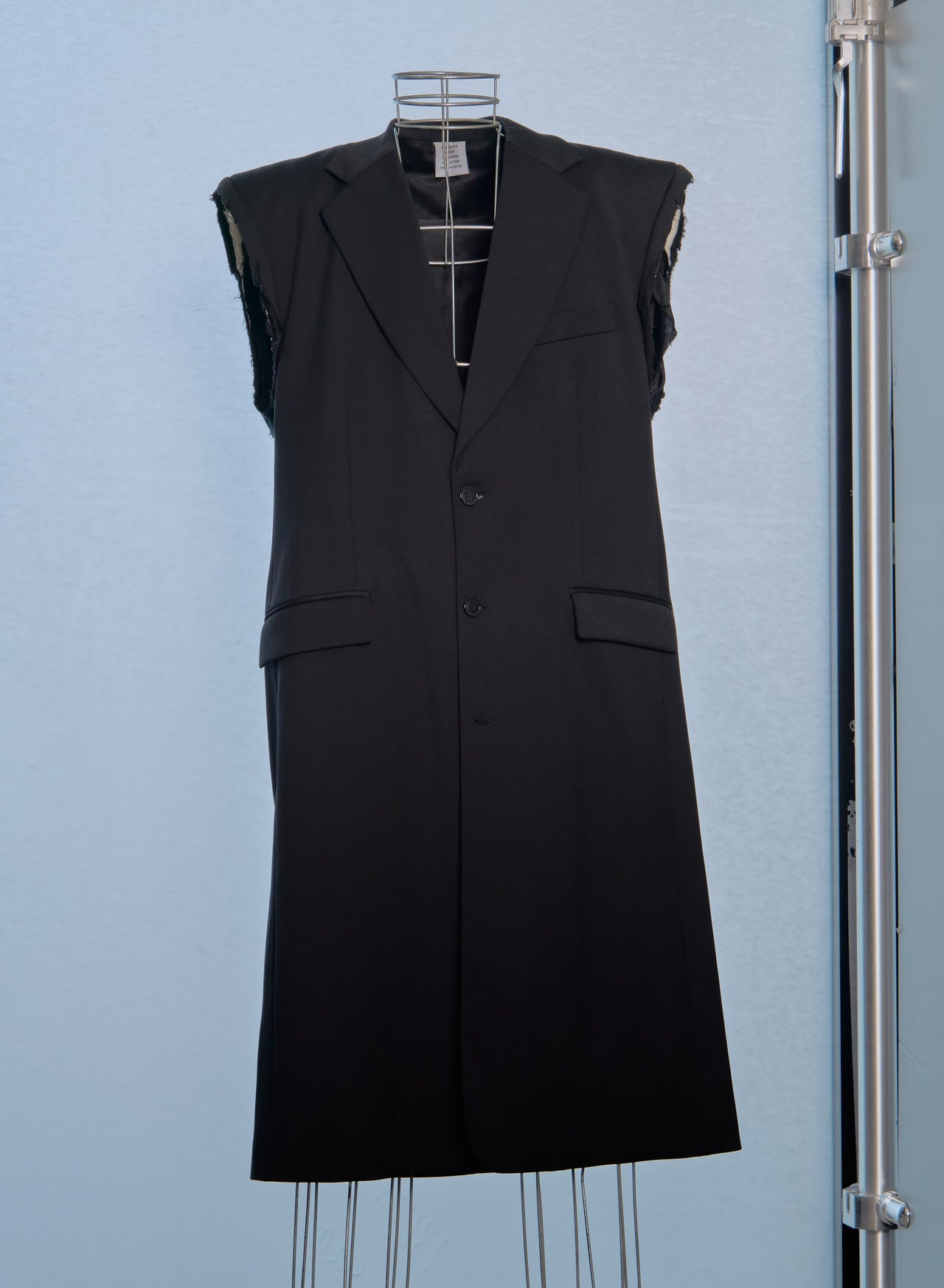 Black sleeveless Vetements coat on a mannequin against a light blue background