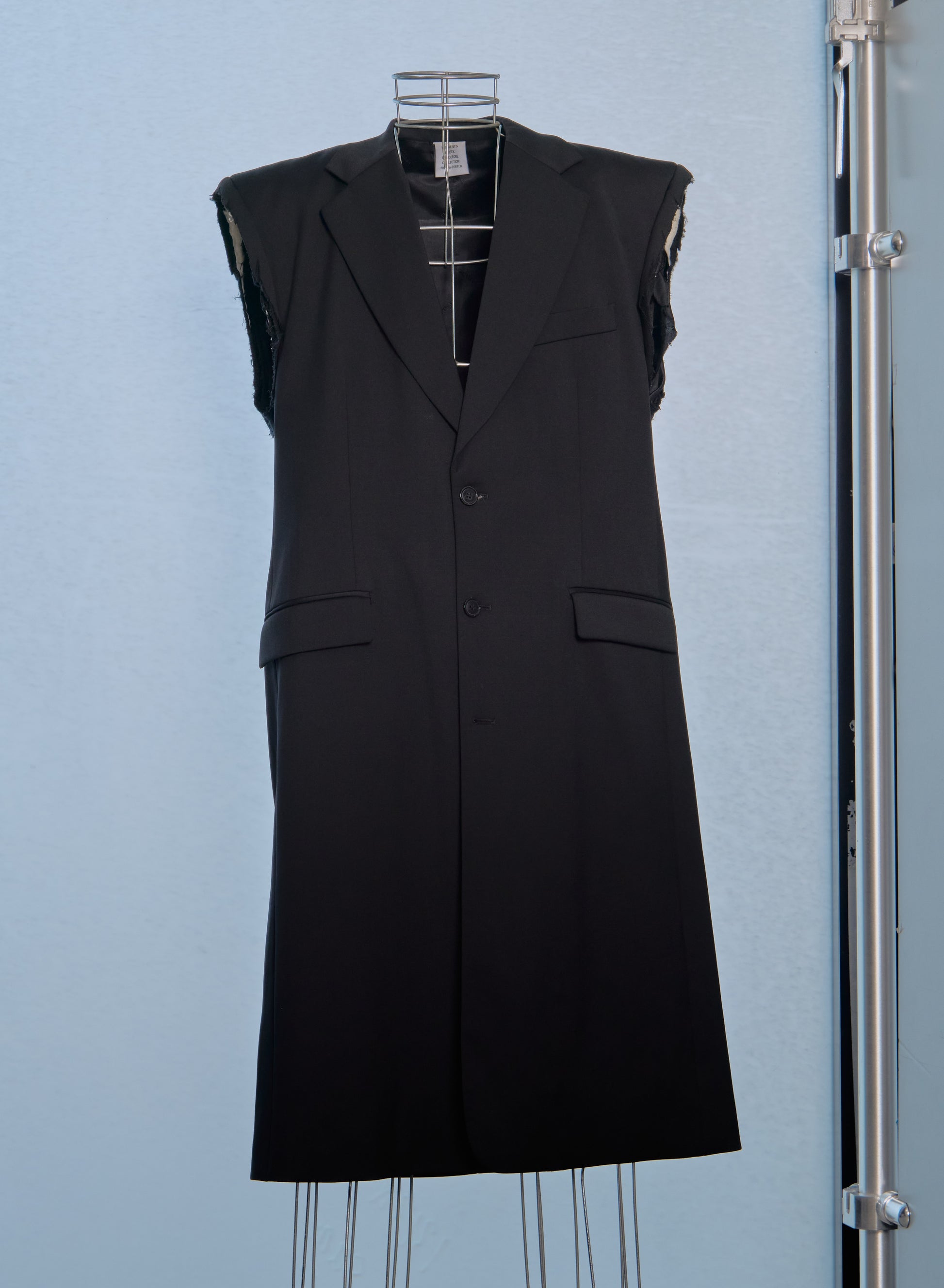 Black sleeveless Vetements coat on a mannequin against a light blue background