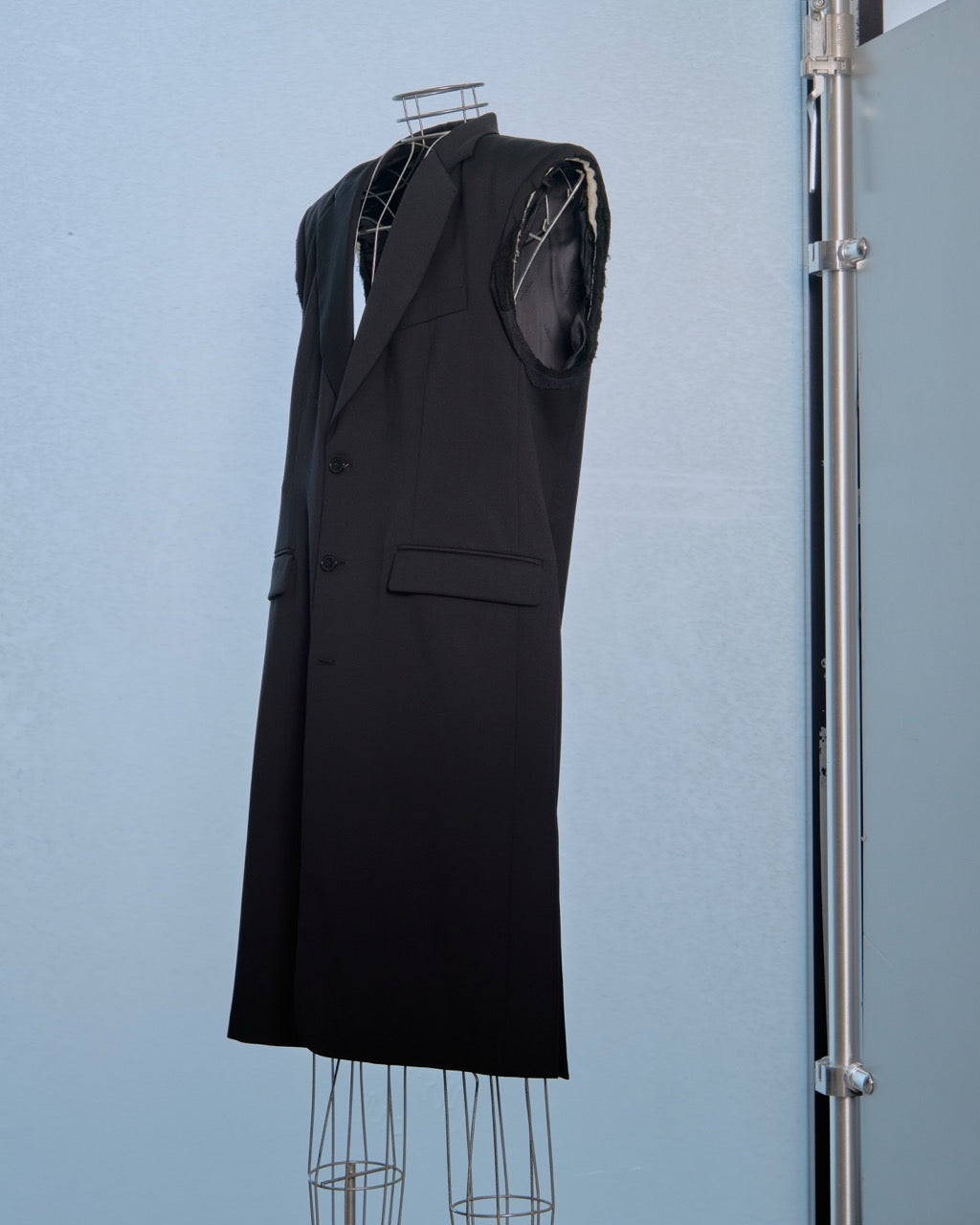 Black sleeveless Vetements coat on a mannequin against a light blue background