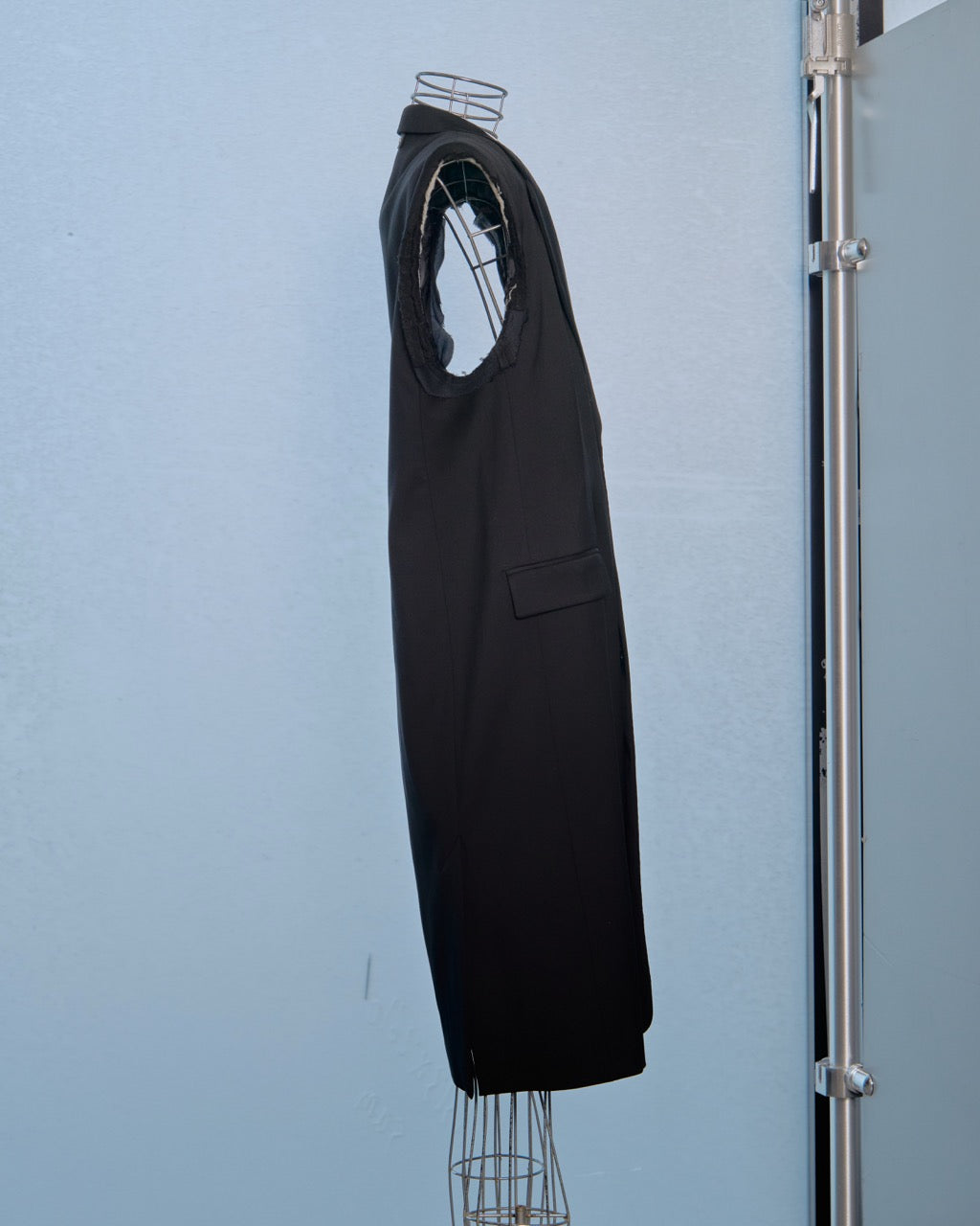 Black sleeveless Vetements jacket on a mannequin against a light blue wall.