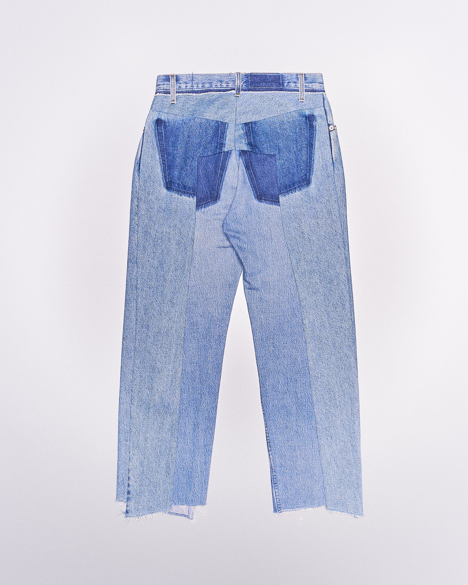 Back view of patchwork Vetements jeans featuring various shades of blue denim. The jeans have an artistic design with asymmetrical, frayed hems and a playful, unique tone.