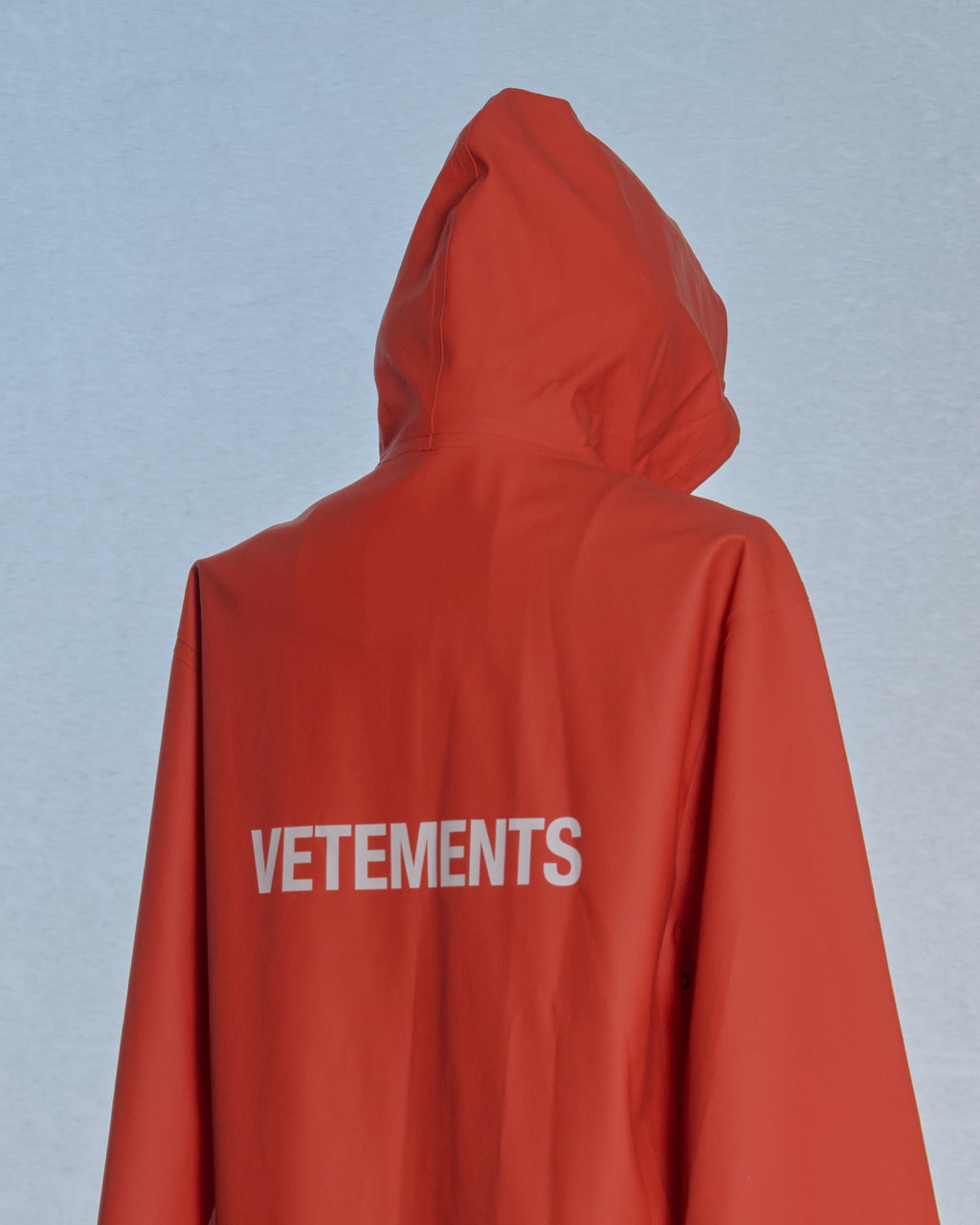 Red hooded jacket with 'VETEMENTS' branding on a light blue background