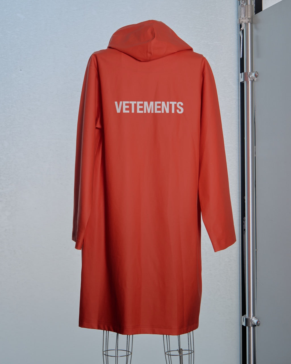 Red coat with 'VETEMENTS' branding on a gray background