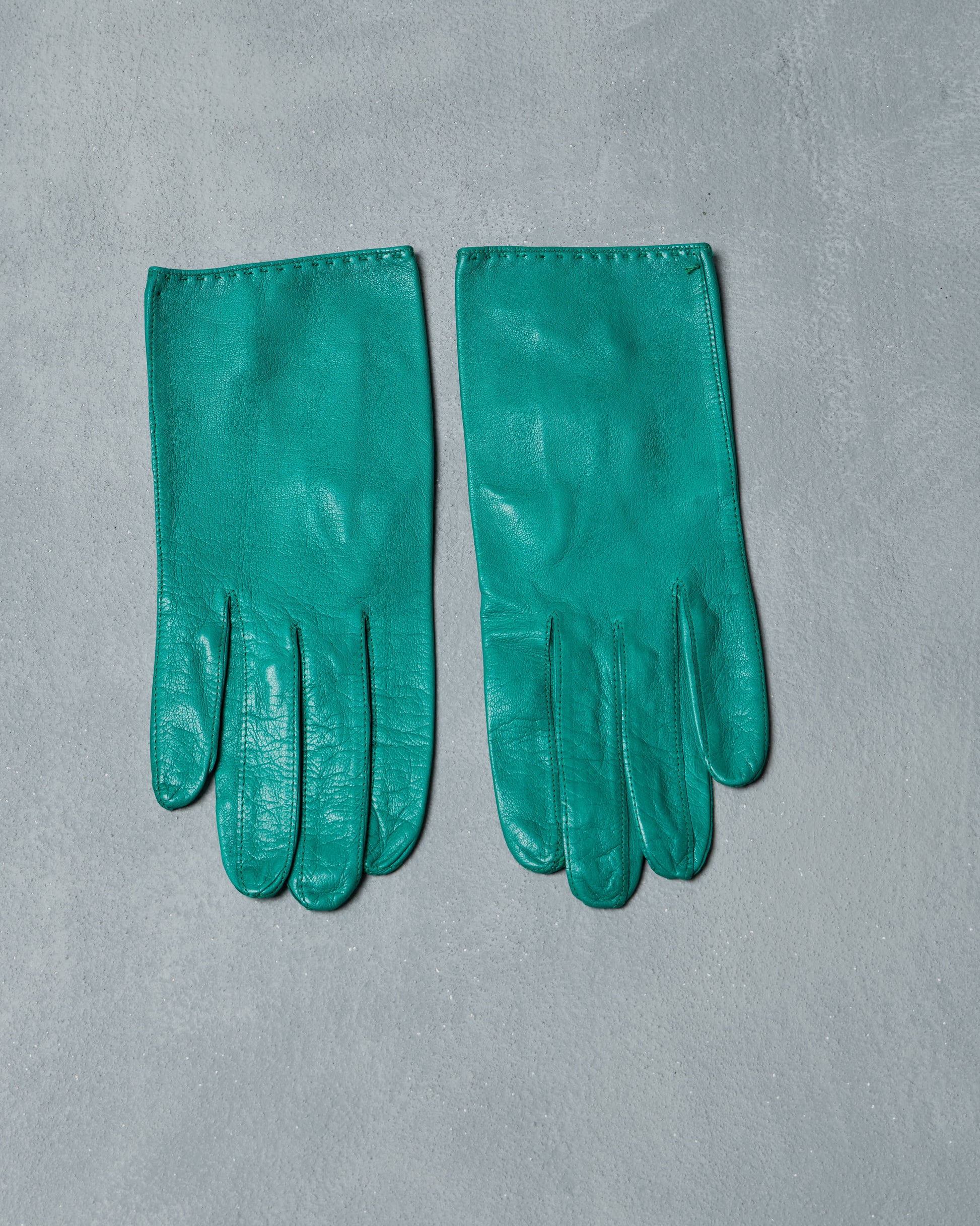 Pair of green vintage gloves on a gray background