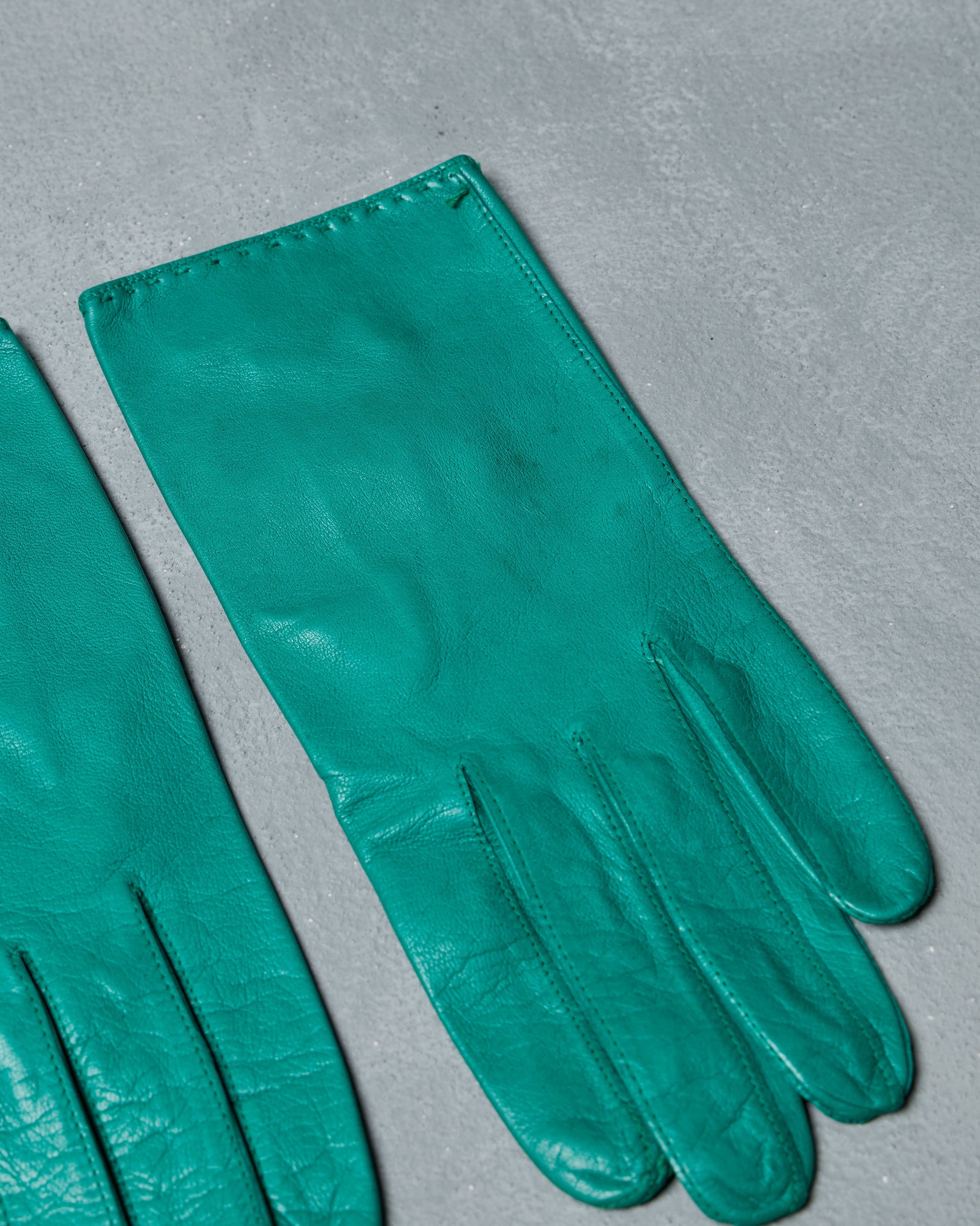 Pair of vintage teal lambskin gloves on a gray background