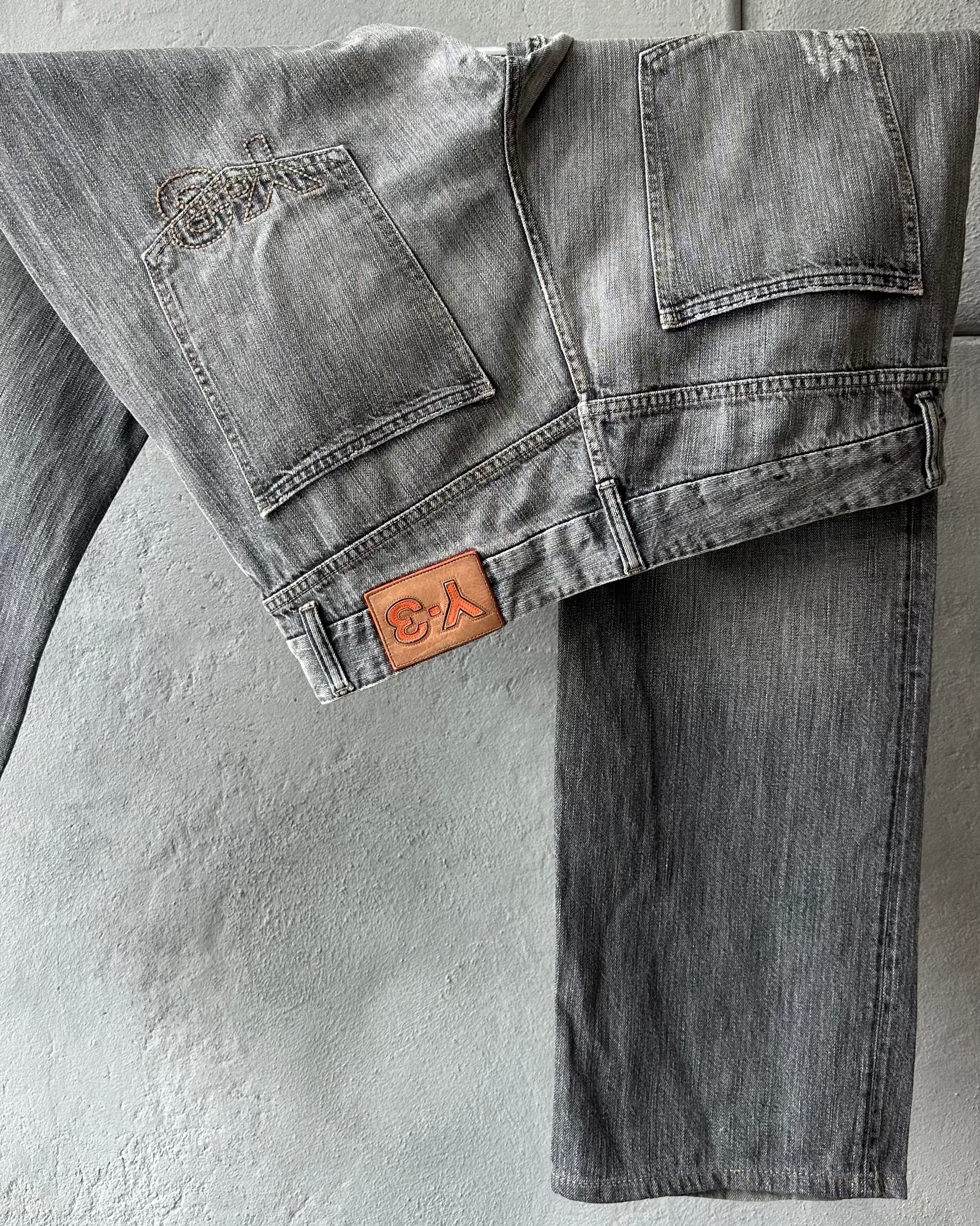 Gray Y-3 jeans with a brand logo on a textured gray background