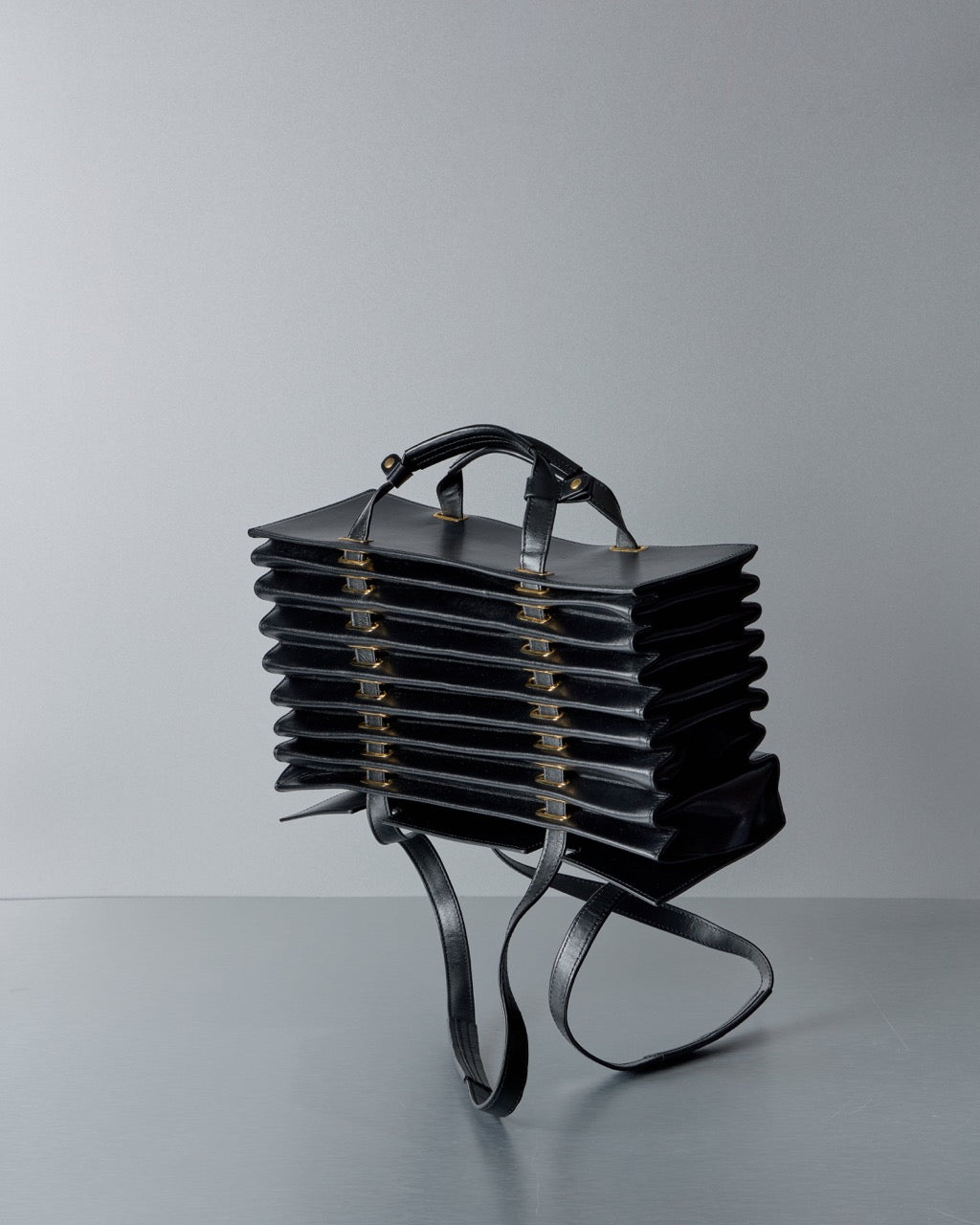 Black leather Y/Project handbag with a unique design on a gray background