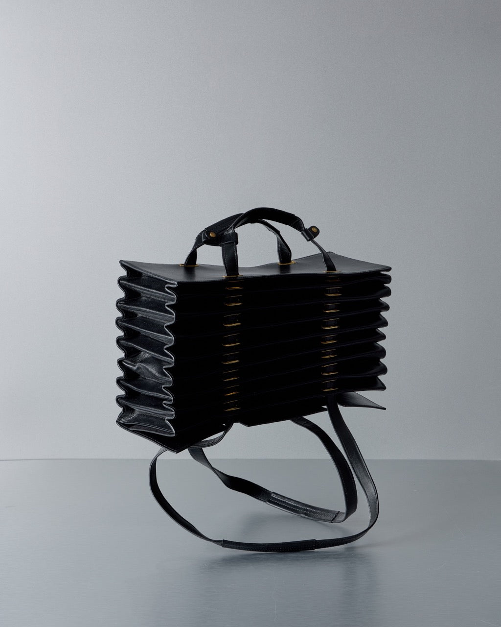 Black leather Y/Project bag with unique design on a gray background