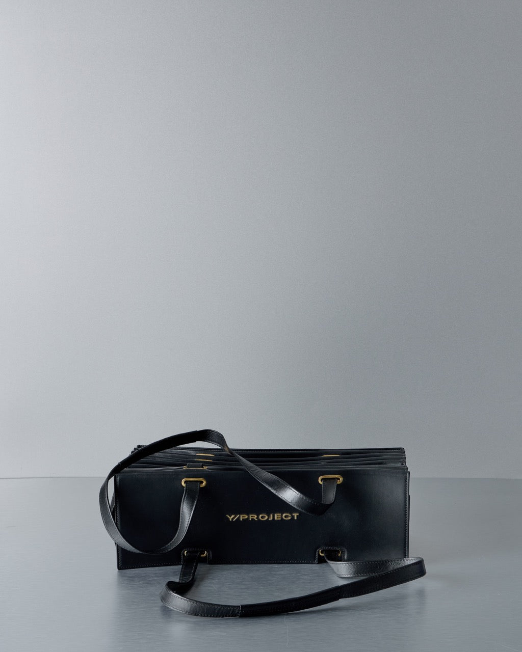 Black leather Y/Project bag with visible branding on a gray background