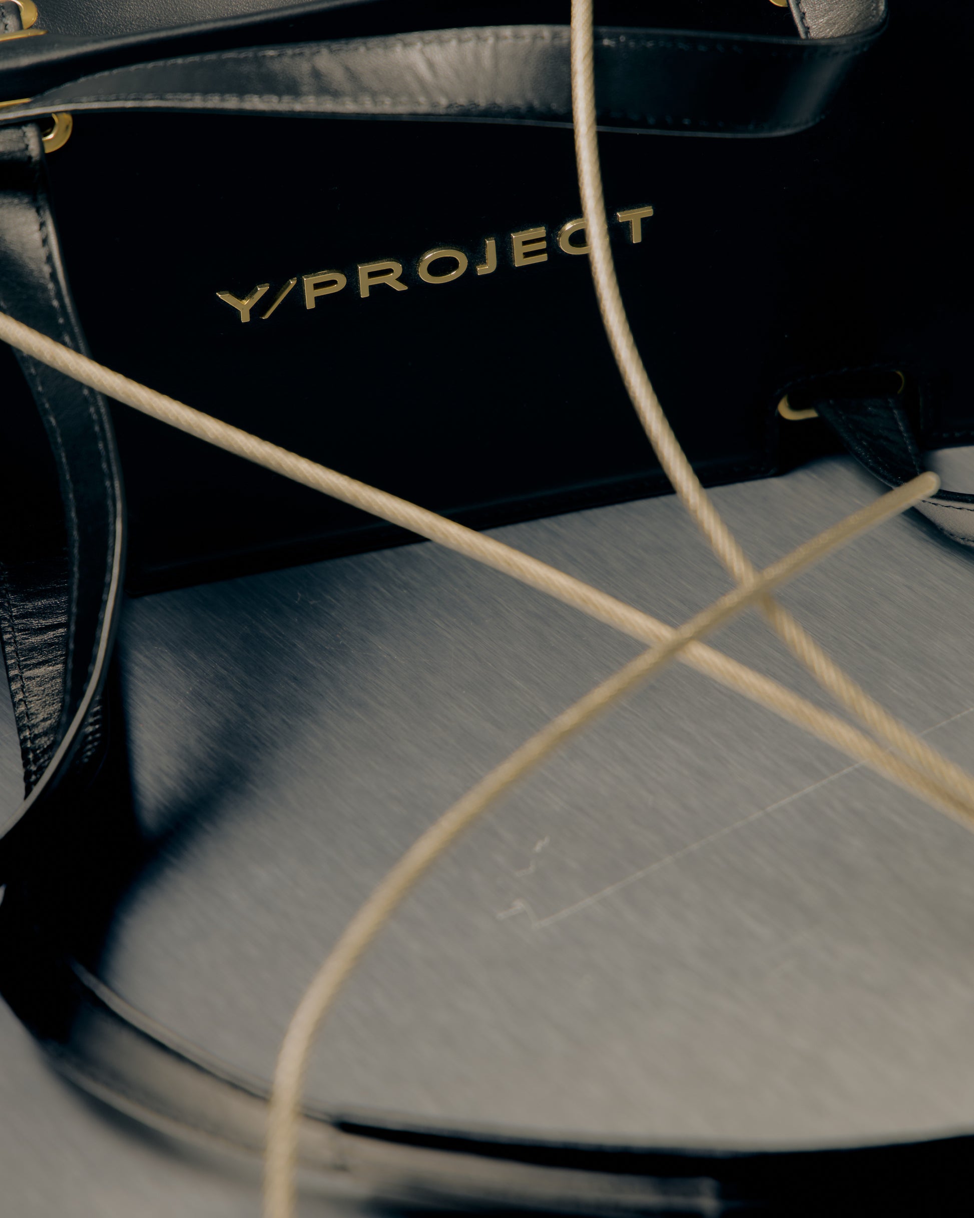 Close-up of a black bag with 'Y/Project' branding on a textured surface.
