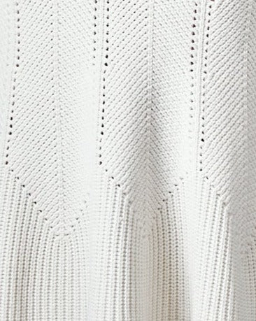 Close-up of a white knitted fabric with a chevron pattern from an Alexander McQueen dress. The texture is soft, with diagonal ribbing and subtle perforations. 