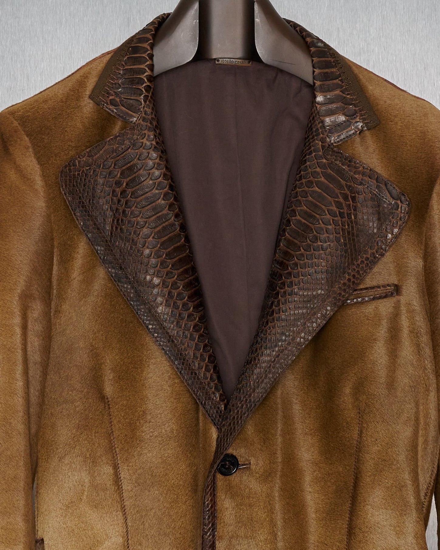 Brown leather Roberto Cavalli jacket with snake skin collar on a mannequin against a neutral background.